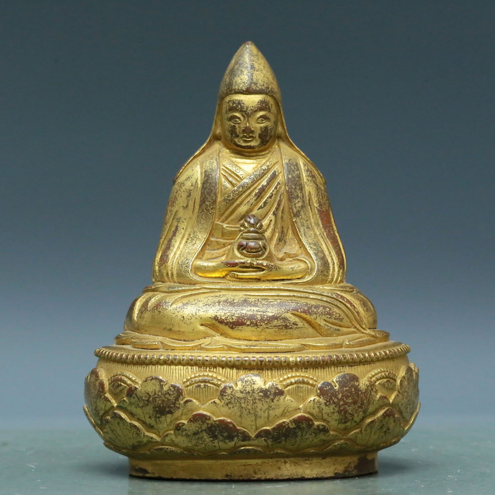 An Archaic Gilt-Bronze Figure Of Tsongkapa: An Archaic Gilt-Bronze Figure Of Tsongkapa. The figure with a dignified expression is rendered clad in long, flowing robes, the voluminous drapery elegantly cascading in folds, surmounted by a