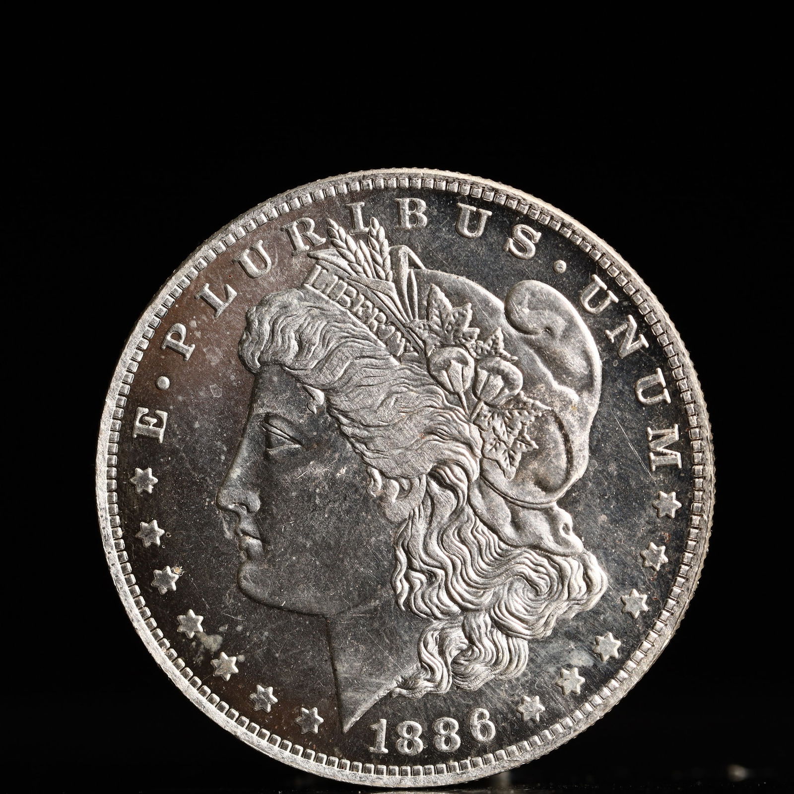 USA Morgan Dollar 1886 Coin: Obv: profile bust with date below and E PLURIBUS UNUM legend and stars around. Rev: eagle with In God we trust above within wreath with UNITED STATES OF AMERICA ONE DOLLAR legend. IN GOD WE TRUST / LI