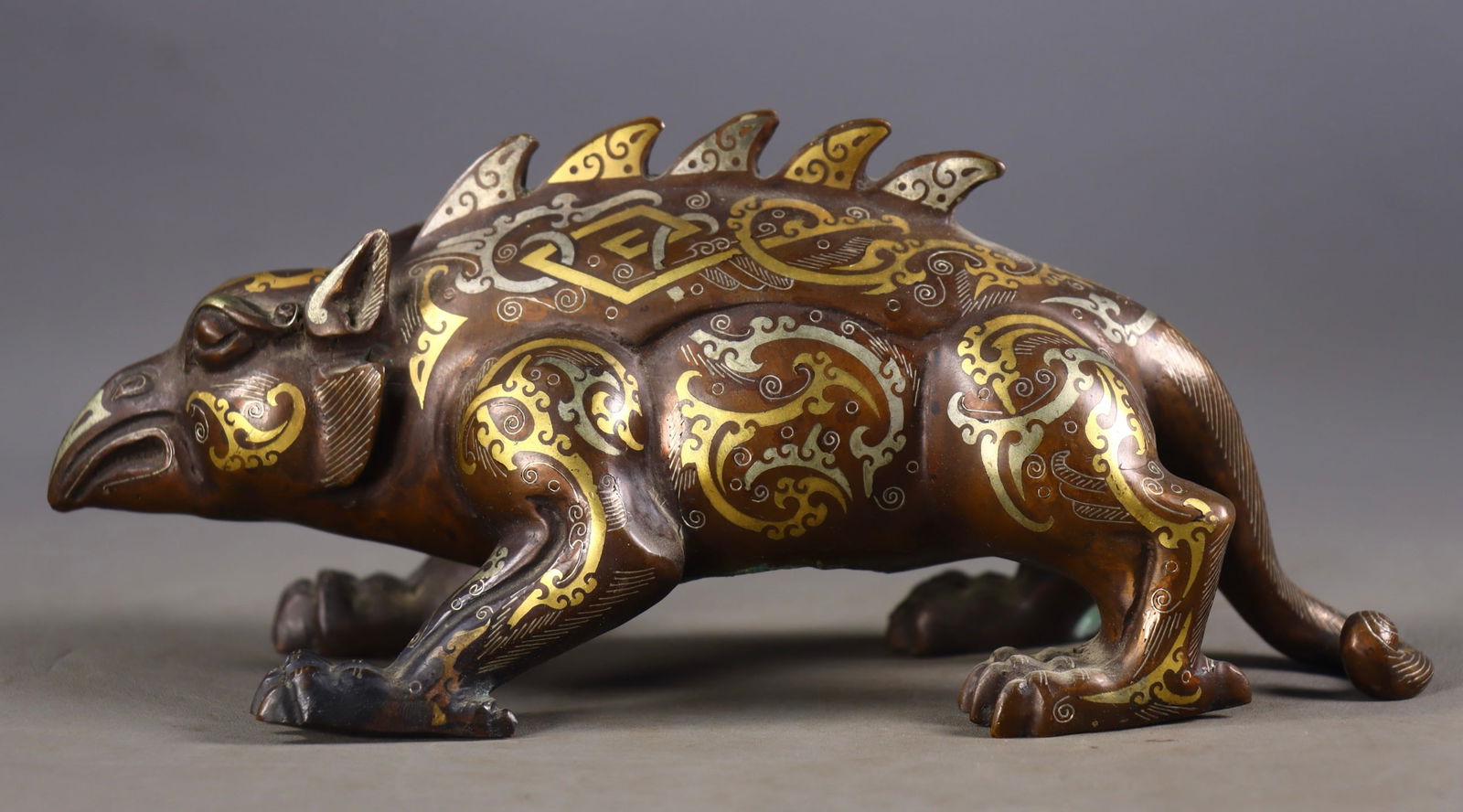 An Exquisite Bronze Inlaid Gold and Silver Auspicious Beast Ornament: An Exquisite Bronze Inlaid Gold and Silver Auspicious Beast Ornament,the Warring States period in China,Size:3.5inx7.9inx3.5in,Weight:812g 