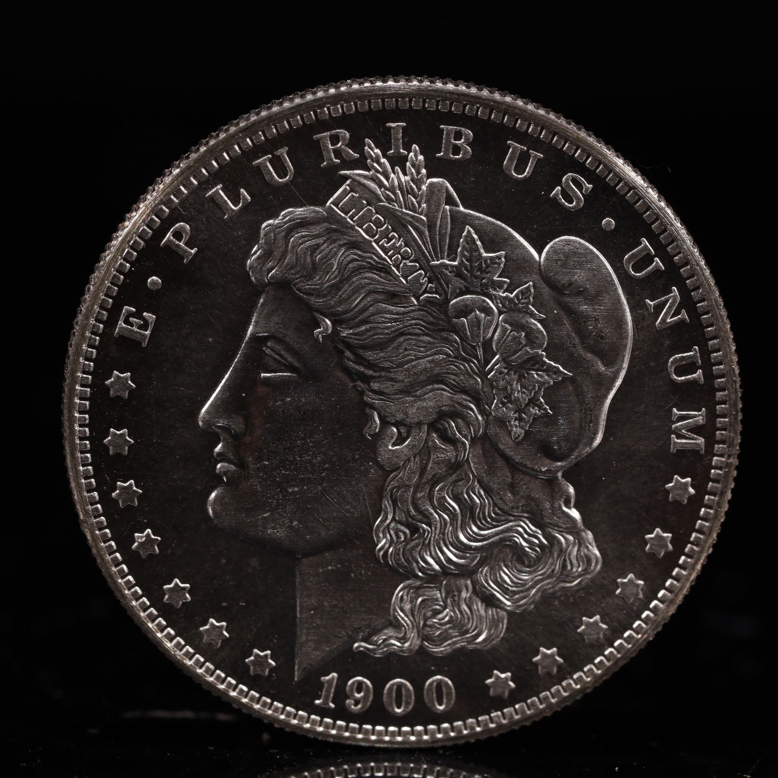 USA Morgan Dollar 1900 Coin: Obv: profile bust with date below and E PLURIBUS UNUM legend and stars around. Rev: eagle with In God we trust above within wreath with UNITED STATES OF AMERICA ONE DOLLAR legend. IN GOD WE TRUST / LI