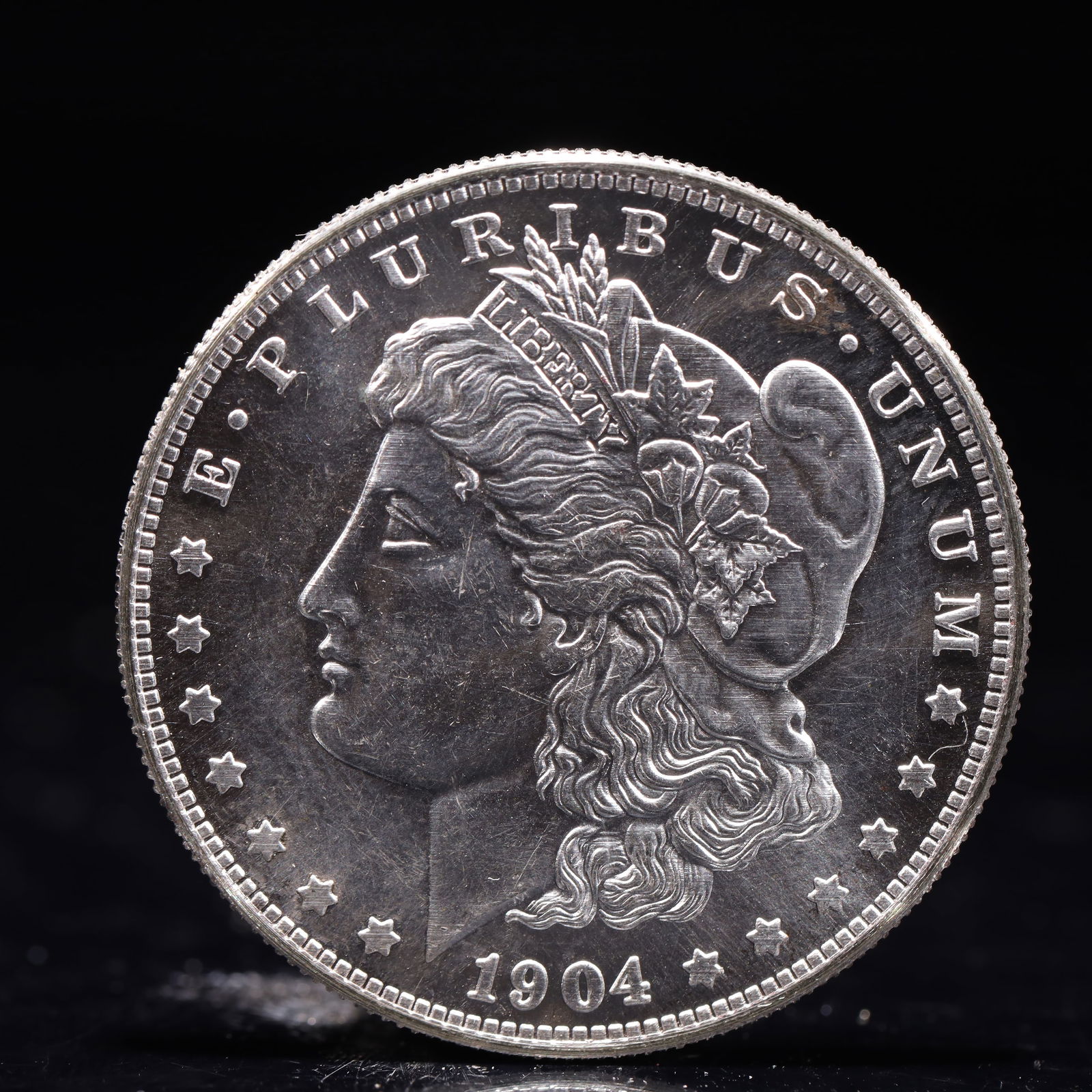USA Morgan Dollar 1904 Coin: Obv: profile bust with date below and E PLURIBUS UNUM legend and stars around. Rev: eagle with In God we trust above within wreath with UNITED STATES OF AMERICA ONE DOLLAR legend. IN GOD WE TRUST / LI