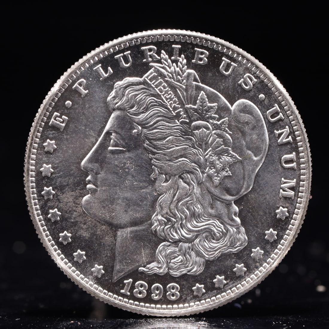 USA Morgan Dollar 1898 Coin: Obv: profile bust with date below and E PLURIBUS UNUM legend and stars around. Rev: eagle with In God we trust above within wreath with UNITED STATES OF AMERICA ONE DOLLAR legend. IN GOD WE TRUST /