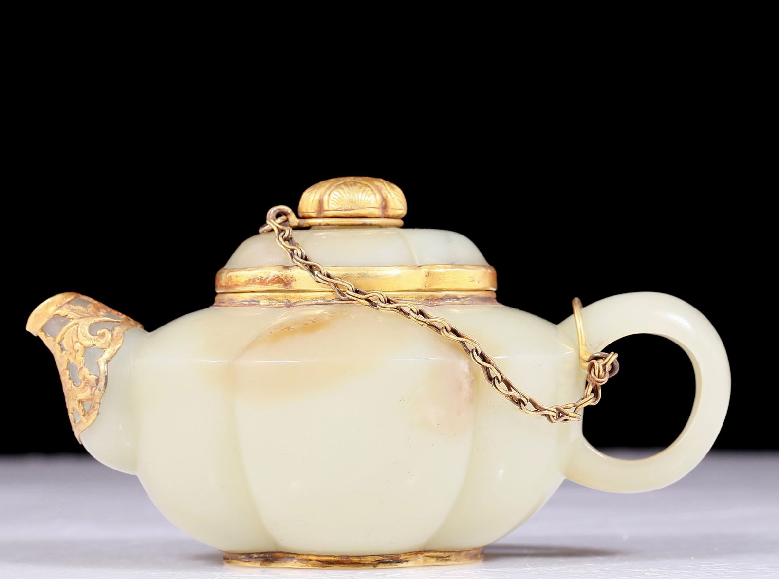 An exquisite white jade teapot covered with gold and floral patterns: An exquisite white jade teapot covered with gold and floral patterns. The jade exhibits delicate, warm and lustrous qualities. The craftsmanship is flawless, the design is exquisite, and the carvings