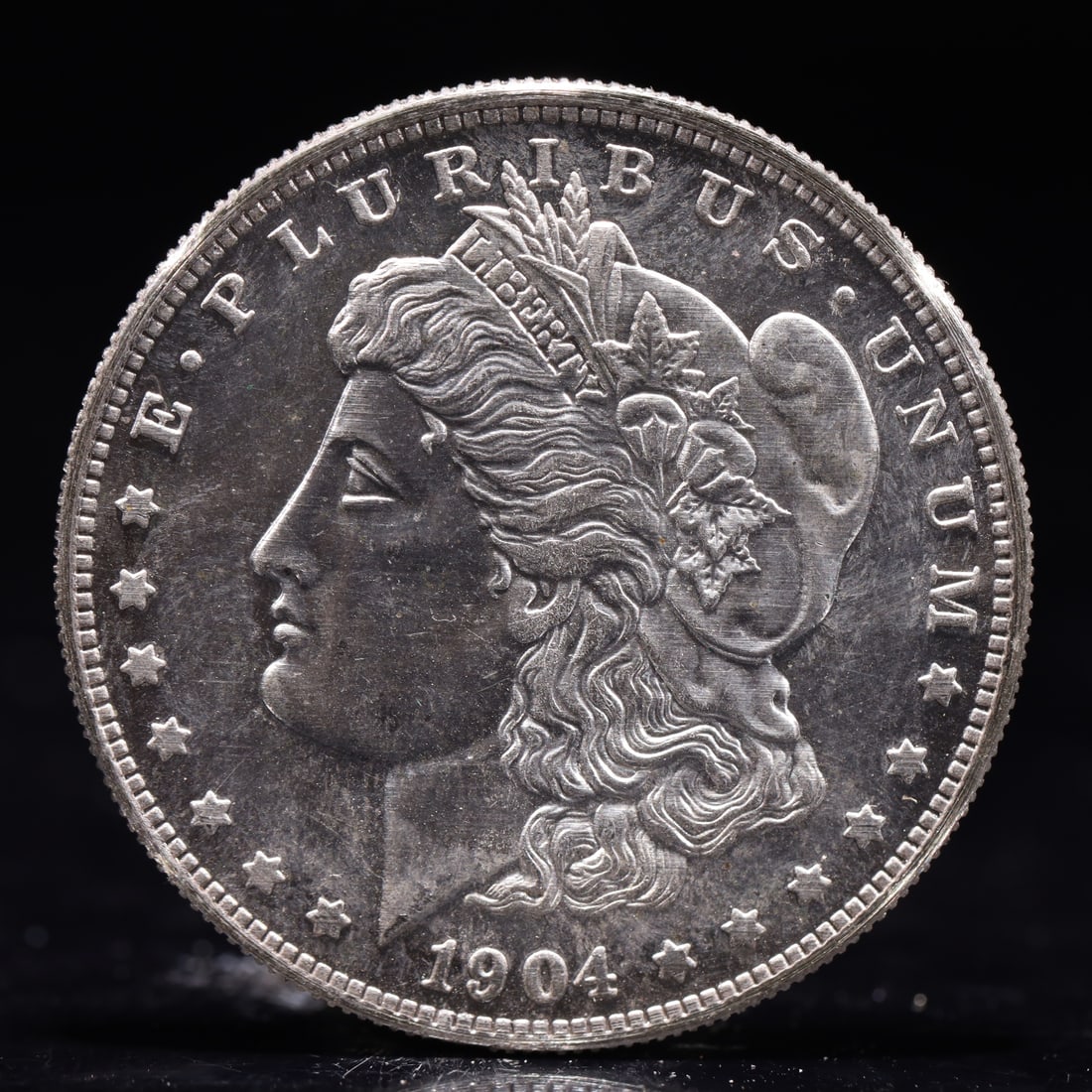 USA Morgan Dollar 1904 Coin: Obv: profile bust with date below and E PLURIBUS UNUM legend and stars around. Rev: eagle with In God we trust above within wreath with UNITED STATES OF AMERICA ONE DOLLAR legend. IN GOD WE TRUST /