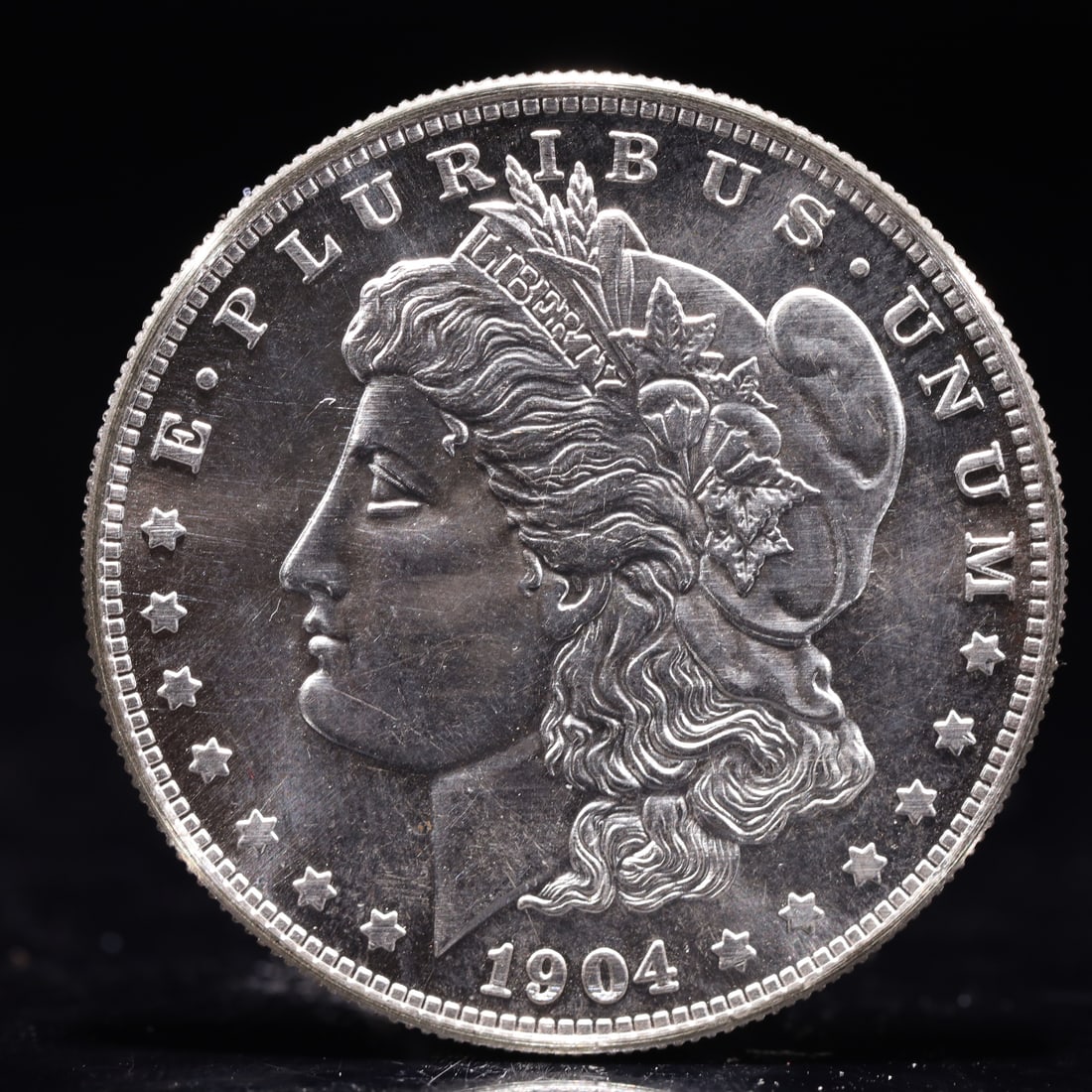 USA Morgan Dollar 1904 Coin: Obv: profile bust with date below and E PLURIBUS UNUM legend and stars around. Rev: eagle with In God we trust above within wreath with UNITED STATES OF AMERICA ONE DOLLAR legend. IN GOD WE TRUST /