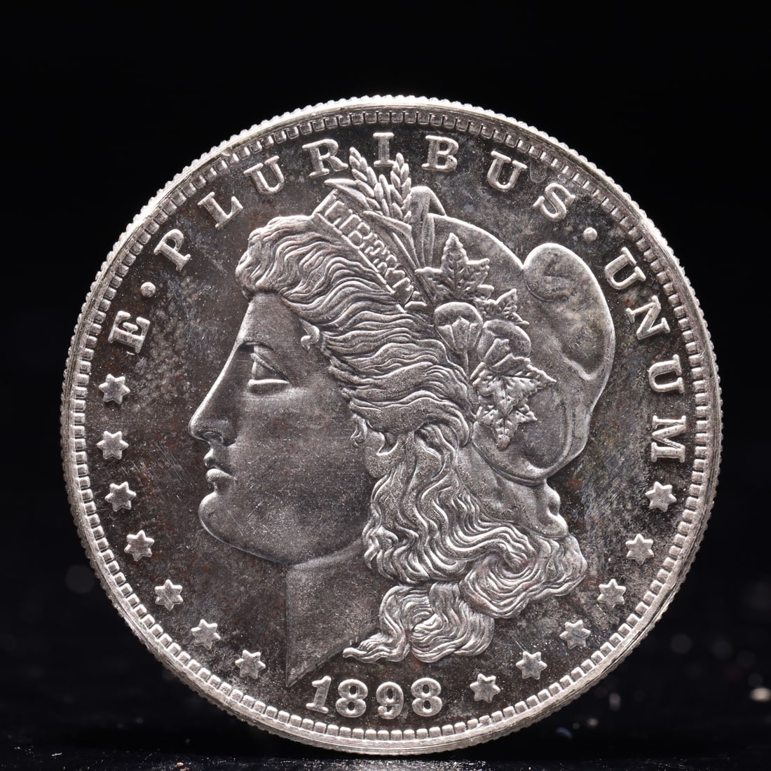 USA Morgan Dollar 1898 Coin: Obv: profile bust with date below and E PLURIBUS UNUM legend and stars around. Rev: eagle with In God we trust above within wreath with UNITED STATES OF AMERICA ONE DOLLAR legend. IN GOD WE TRUST /