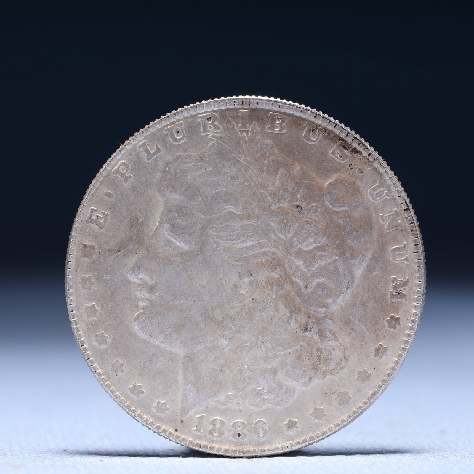 USA Morgan Dollar 1886 Coin: Obv: profile bust with date below and E PLURIBUS UNUM legend and stars around. Rev: eagle with In God we trust above within wreath with UNITED STATES OF AMERICA ONE DOLLAR legend. IN GOD WE TRUST / LI
