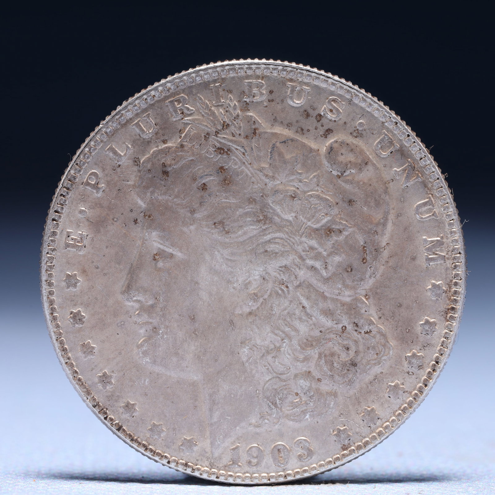 USA Morgan Dollar 1903 Coin: Obv: profile bust with date below and E PLURIBUS UNUM legend and stars around. Rev: eagle with In God we trust above within wreath with UNITED STATES OF AMERICA ONE DOLLAR legend. IN GOD WE TRUST / LI