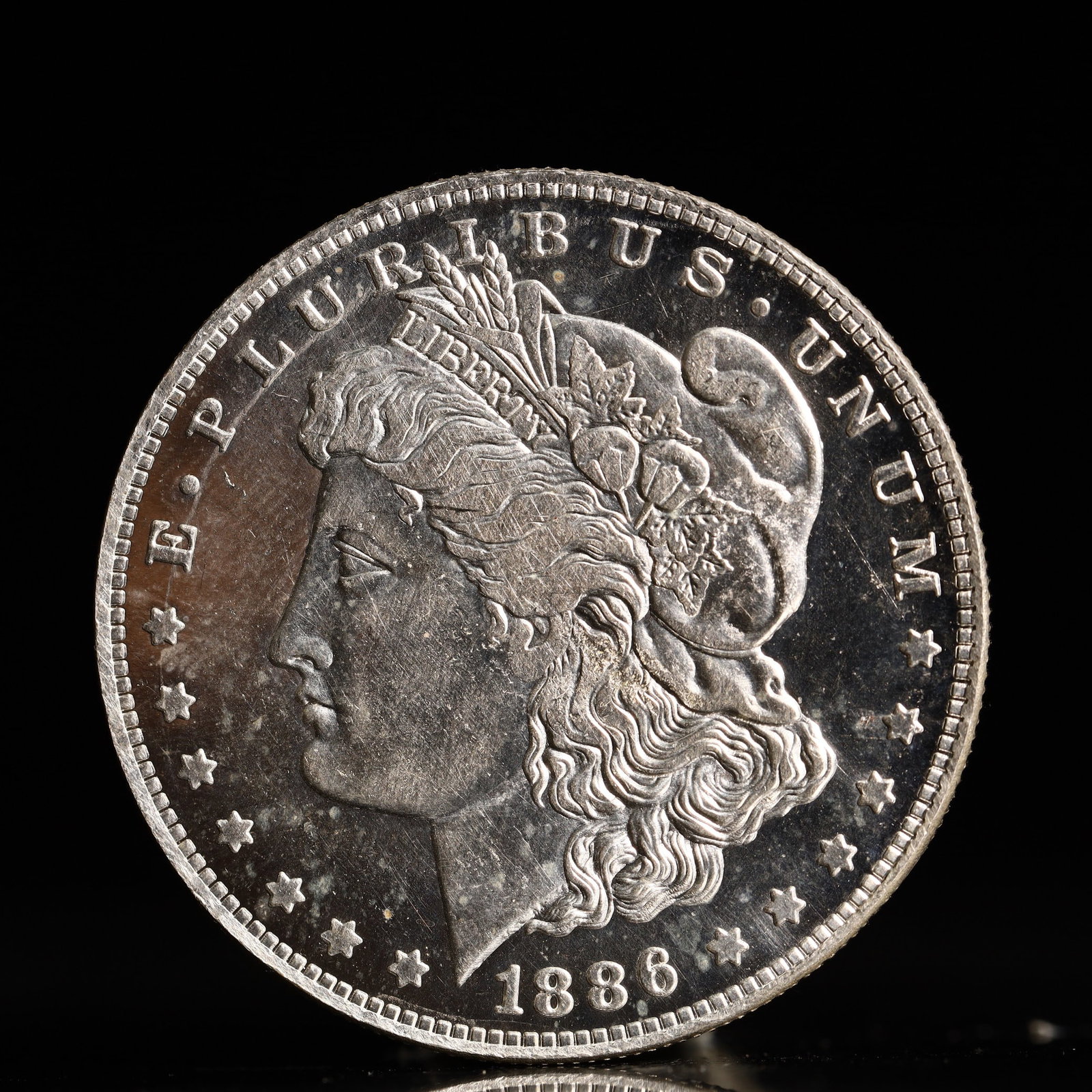 USA Morgan Dollar 1886 Coin: Obv: profile bust with date below and E PLURIBUS UNUM legend and stars around. Rev: eagle with In God we trust above within wreath with UNITED STATES OF AMERICA ONE DOLLAR legend. IN GOD WE TRUST / LI