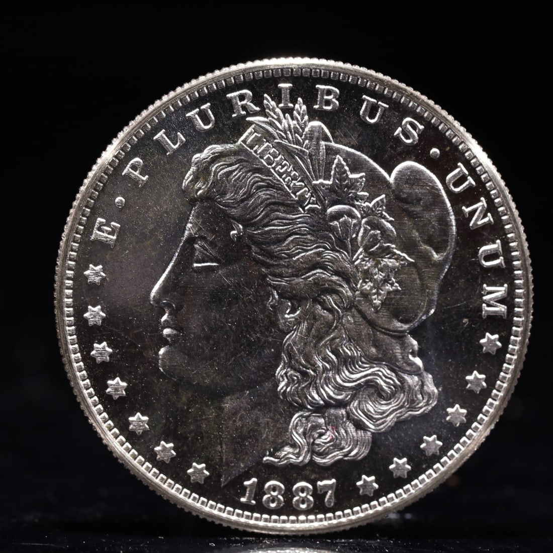 USA Morgan Dollar 1887 Coin: Obv: profile bust with date below and E PLURIBUS UNUM legend and stars around. Rev: eagle with In God we trust above within wreath with UNITED STATES OF AMERICA ONE DOLLAR legend. IN GOD WE TRUST / LI