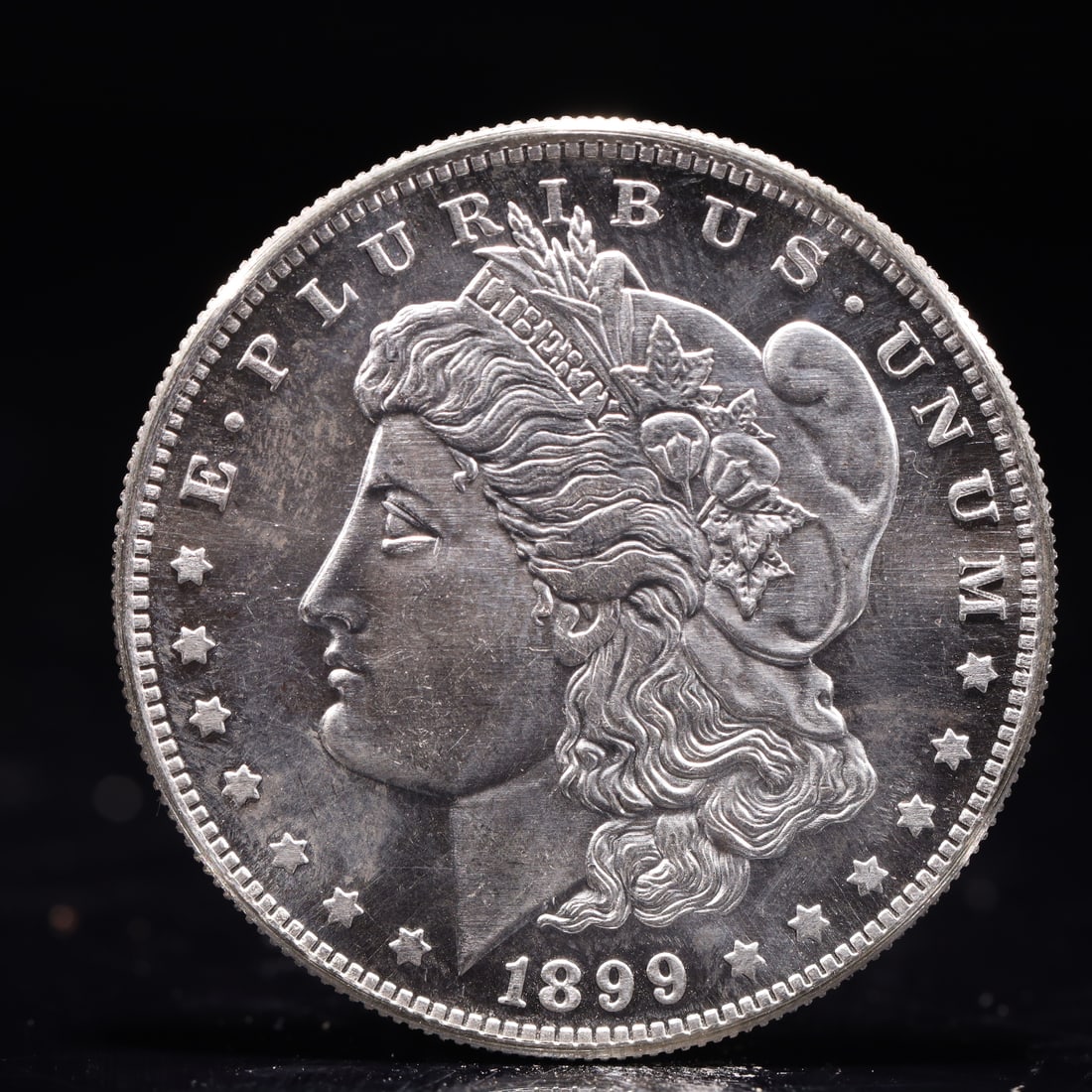 USA Morgan Dollar 1899 Coin: Obv: profile bust with date below and E PLURIBUS UNUM legend and stars around. Rev: eagle with In God we trust above within wreath with UNITED STATES OF AMERICA ONE DOLLAR legend. IN GOD WE TRUST / LI