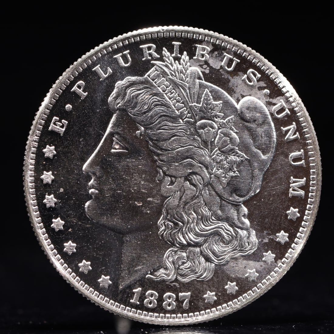 USA Morgan Dollar 1887 Coin: Obv: profile bust with date below and E PLURIBUS UNUM legend and stars around. Rev: eagle with In God we trust above within wreath with UNITED STATES OF AMERICA ONE DOLLAR legend. IN GOD WE TRUST / LI