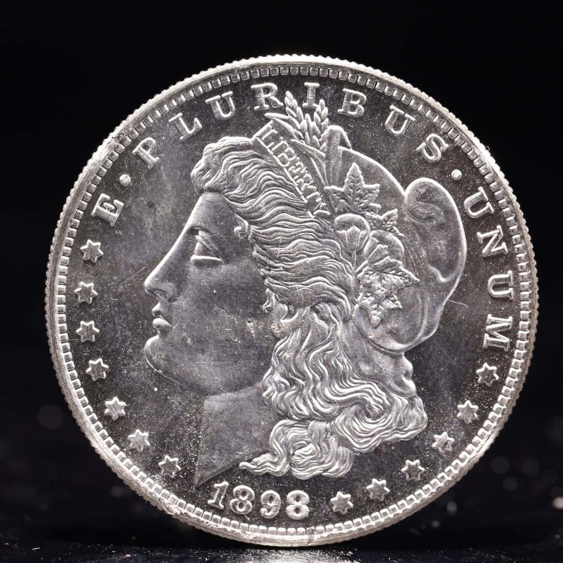 USA Morgan Dollar 1898 Coin: Obv: profile bust with date below and E PLURIBUS UNUM legend and stars around. Rev: eagle with In God we trust above within wreath with UNITED STATES OF AMERICA ONE DOLLAR legend. IN GOD WE TRUST / LI