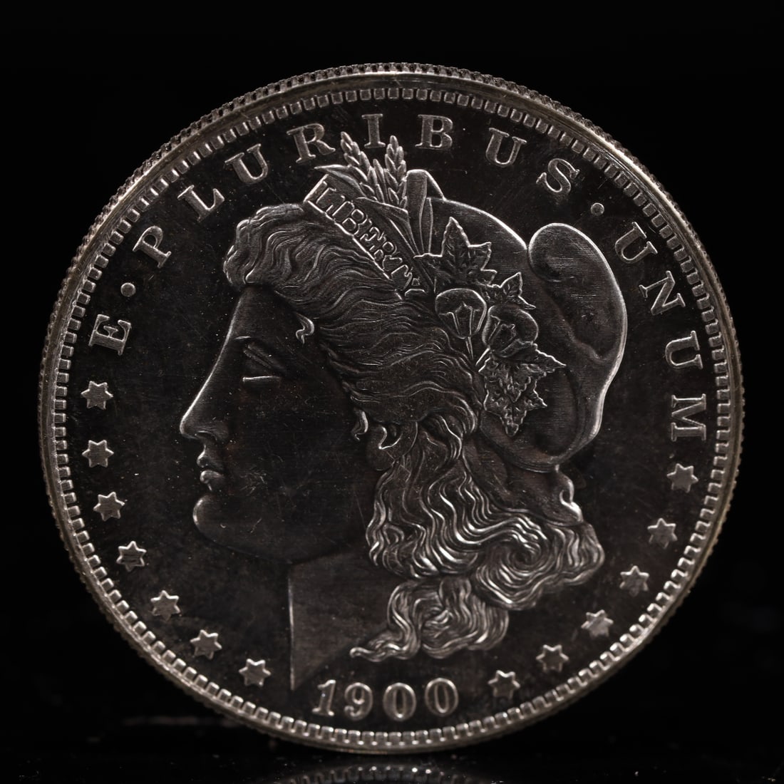 USA Morgan Dollar 1900 Coin: Obv: profile bust with date below and E PLURIBUS UNUM legend and stars around. Rev: eagle with In God we trust above within wreath with UNITED STATES OF AMERICA ONE DOLLAR legend. IN GOD WE TRUST / LI