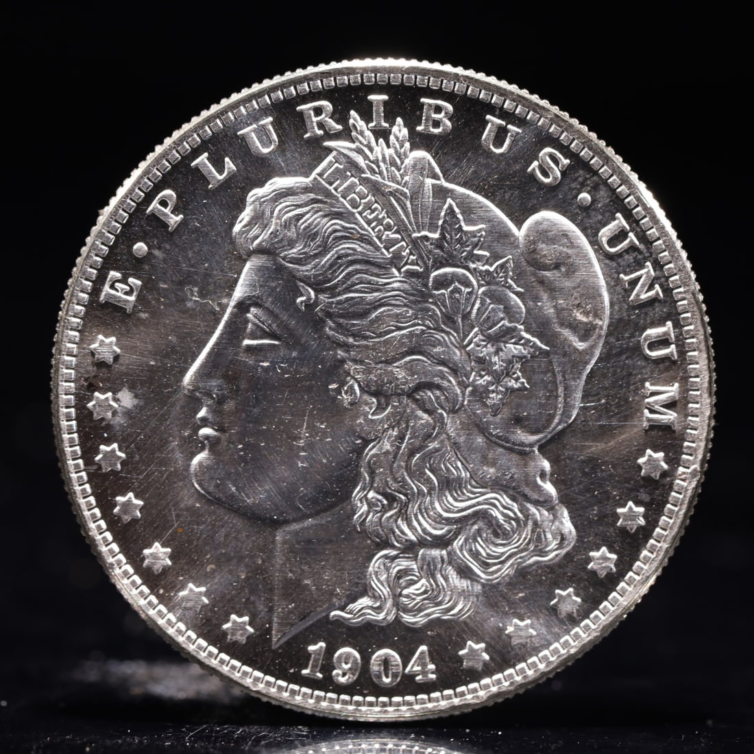 USA Morgan Dollar 1904 Coin: Obv: profile bust with date below and E PLURIBUS UNUM legend and stars around. Rev: eagle with In God we trust above within wreath with UNITED STATES OF AMERICA ONE DOLLAR legend. IN GOD WE TRUST / LI