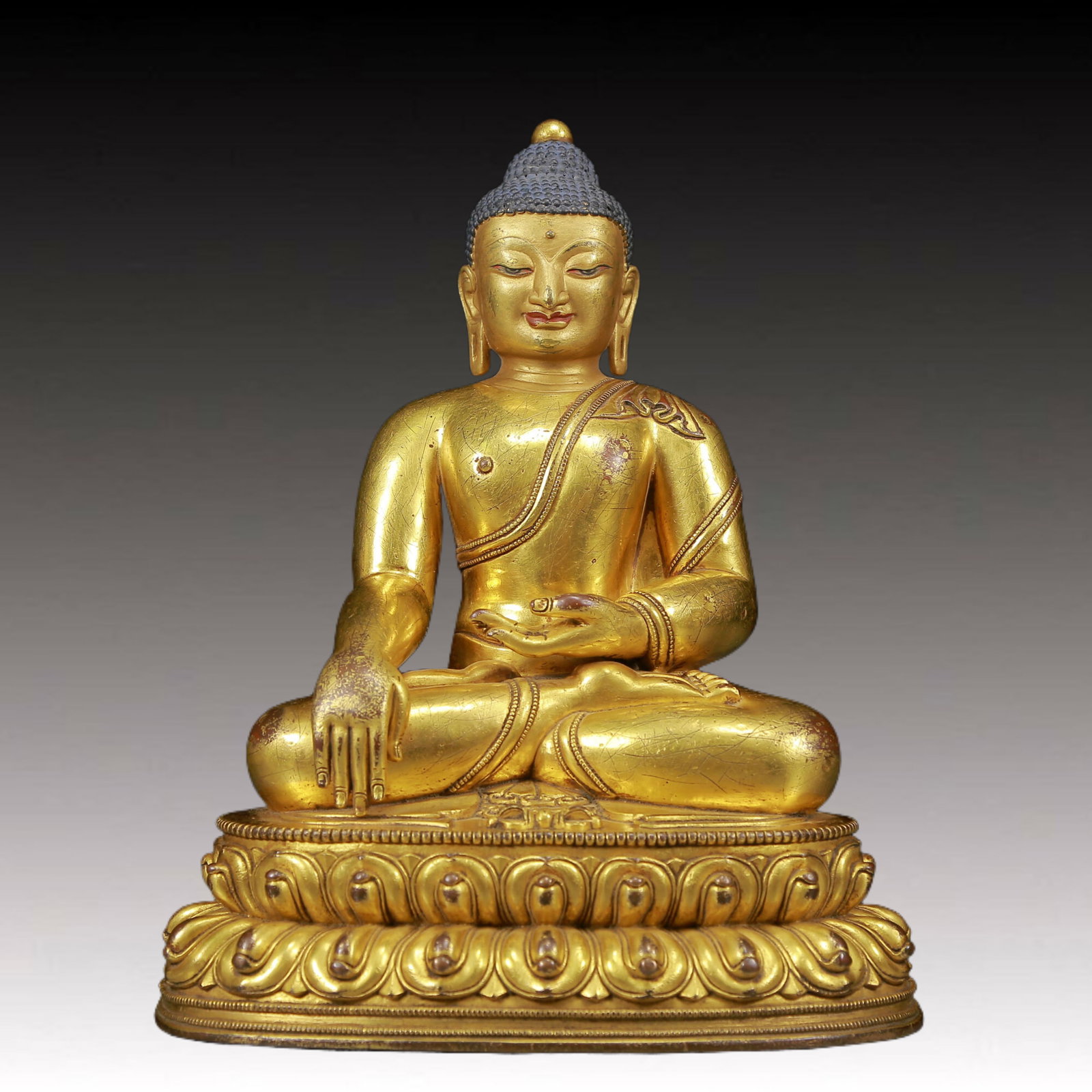 A solemn gilt bronze statue of Sakyamuni: solemn gilt bronze statue of Sakyamuni, Ming Dynasty, China. The Buddha's face has a calm, kind and serene expression, and his hands and fingers show beautiful lines and proportions to demonstrate the