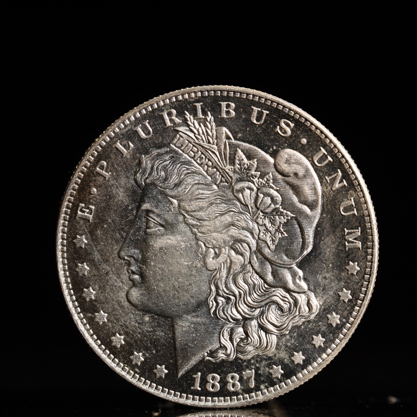 USA Morgan Dollar 1887 Coin: Obv: profile bust with date below and E PLURIBUS UNUM legend and stars around. Rev: eagle with In God we trust above within wreath with UNITED STATES OF AMERICA ONE DOLLAR legend. IN GOD WE TRUST / LI