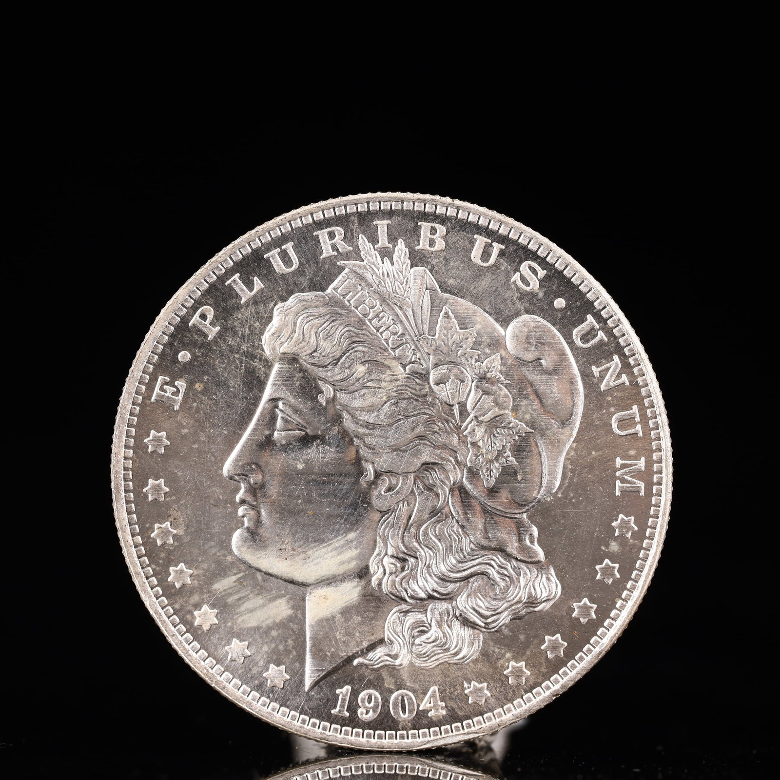 USA Morgan Dollar 1904 Coin: Obv: profile bust with date below and E PLURIBUS UNUM legend and stars around. Rev: eagle with In God we trust above within wreath with UNITED STATES OF AMERICA ONE DOLLAR legend. IN GOD WE TRUST / LI