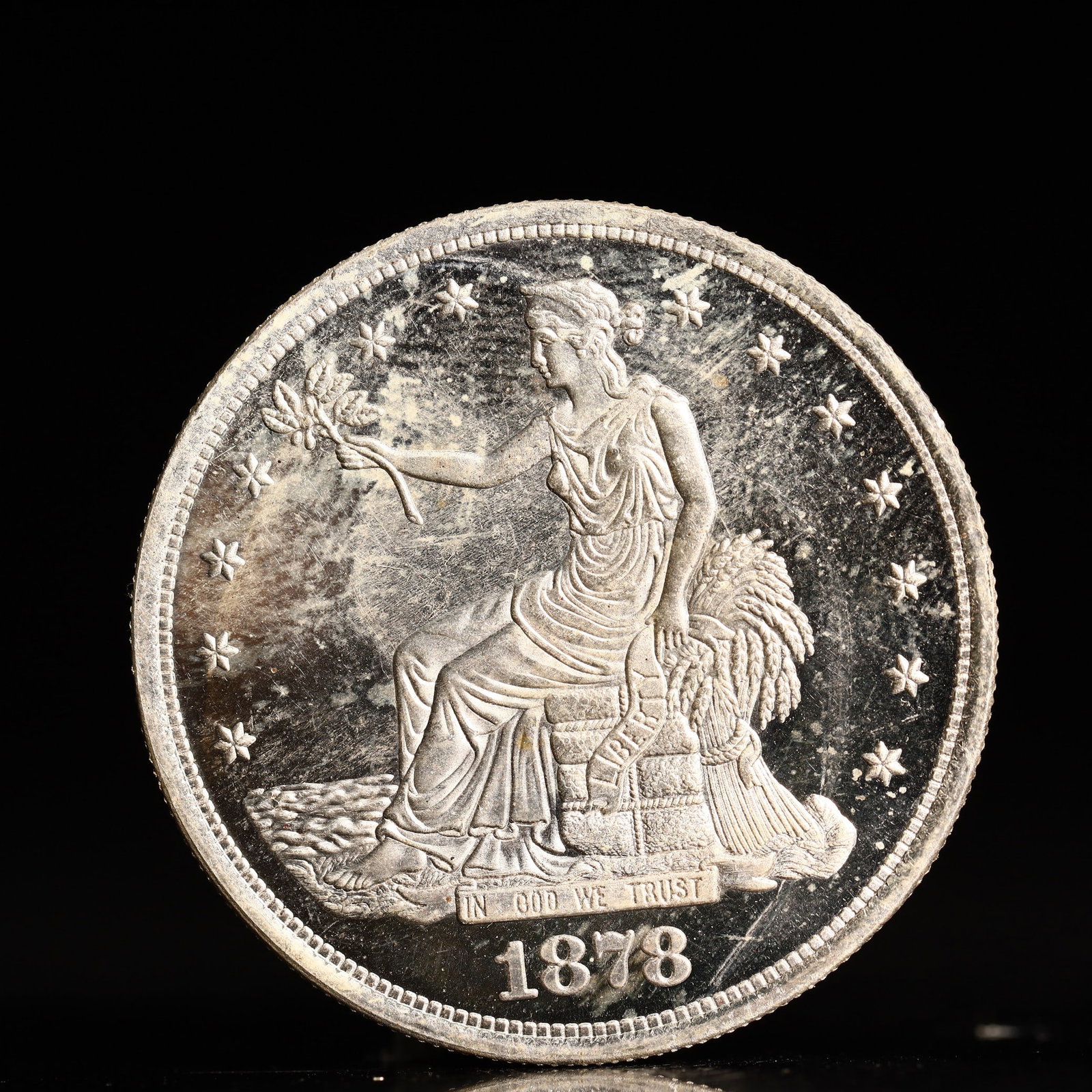 USA Trade Dollar 1878 Coin: American coin. Obverse: Liberty seated on a pedestal facing the sea to the left holding olive branches surrounded by 13 stars. IN GOD WE TRUST / LIBERTY / 1878. Reverse: An eagle holding branches with