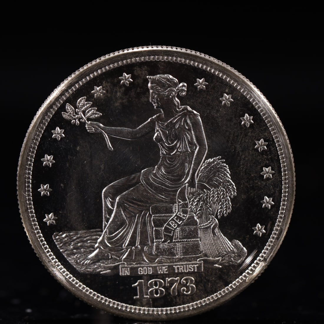 USA Trade Dollar 1873 Coin: American coin. Obverse: Liberty seated on a pedestal facing the sea to the left holding olive branches surrounded by 13 stars. IN GOD WE TRUST / LIBERTY / 1873. Reverse: An eagle holding branches with