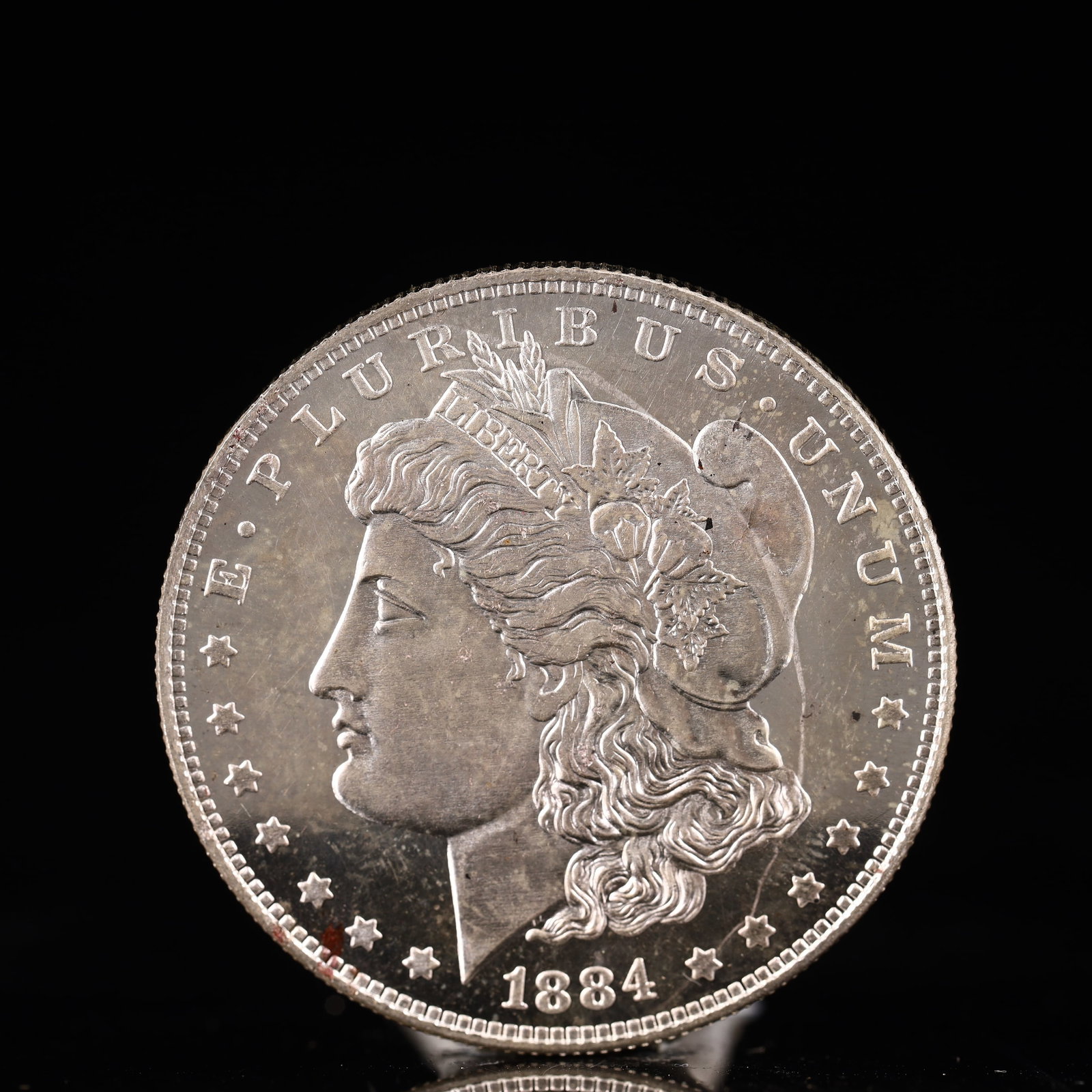 USA Morgan Dollar 1884 Coin: Obv: profile bust with date below and E PLURIBUS UNUM legend and stars around. Rev: eagle with In God we trust above within wreath with UNITED STATES OF AMERICA ONE DOLLAR legend. IN GOD WE TRUST / LI