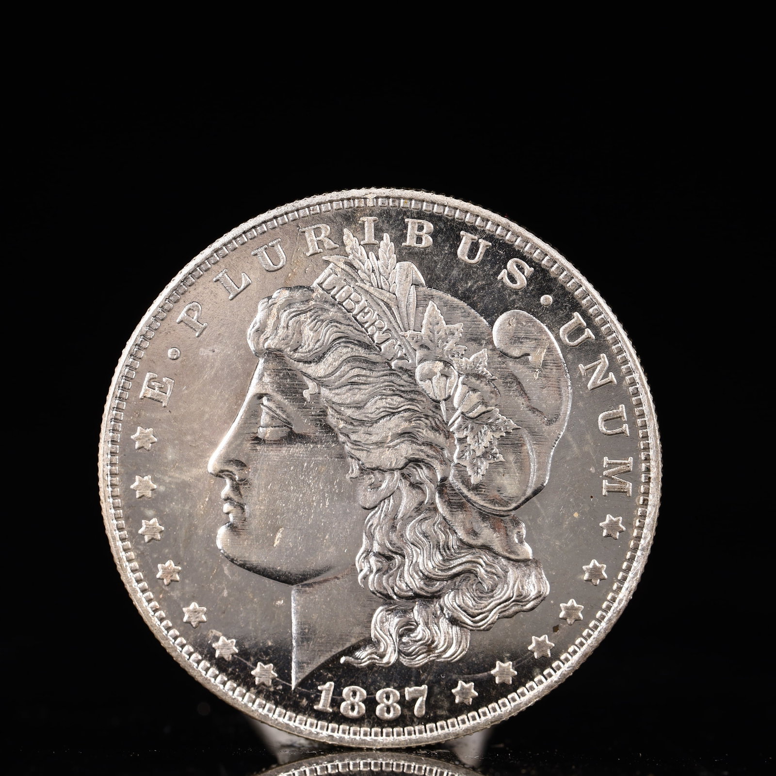 USA Morgan Dollar 1887 Coin: Obv: profile bust with date below and E PLURIBUS UNUM legend and stars around. Rev: eagle with In God we trust above within wreath with UNITED STATES OF AMERICA ONE DOLLAR legend. IN GOD WE TRUST / LI