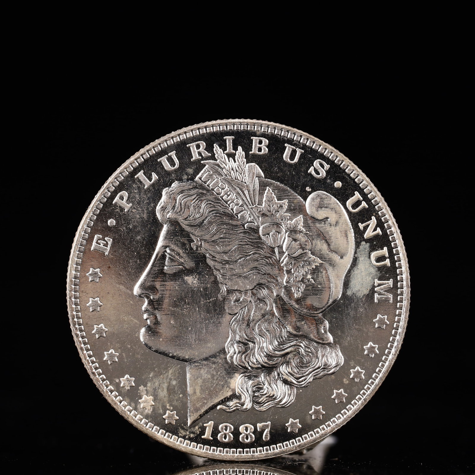 USA Morgan Dollar 1887 Coin: Obv: profile bust with date below and E PLURIBUS UNUM legend and stars around. Rev: eagle with In God we trust above within wreath with UNITED STATES OF AMERICA ONE DOLLAR legend. IN GOD WE TRUST /