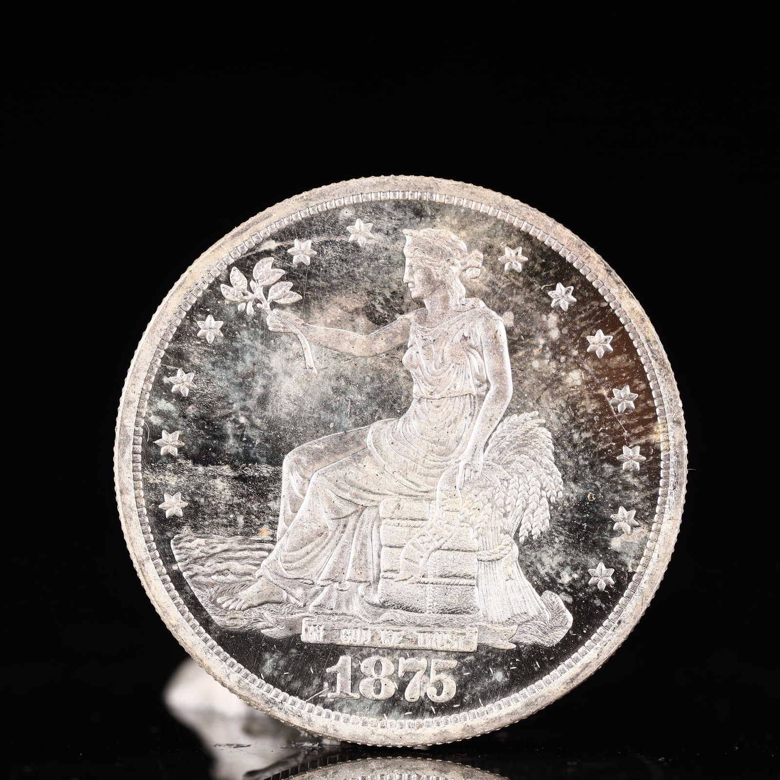 USA Trade Dollar 1875 Coin: American coin. Obverse: Liberty seated on a pedestal facing the sea to the left holding olive branches surrounded by 13 stars. IN GOD WE TRUST / LIBERTY / 1875. Reverse: An eagle holding branches with