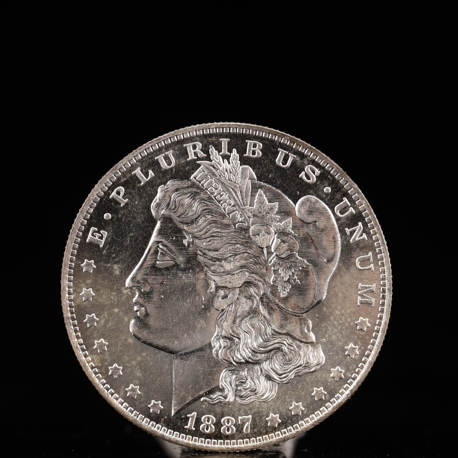 USA Morgan Dollar 1887 Coin: Obv: profile bust with date below and E PLURIBUS UNUM legend and stars around. Rev: eagle with In God we trust above within wreath with UNITED STATES OF AMERICA ONE DOLLAR legend. IN GOD WE TRUST / LI