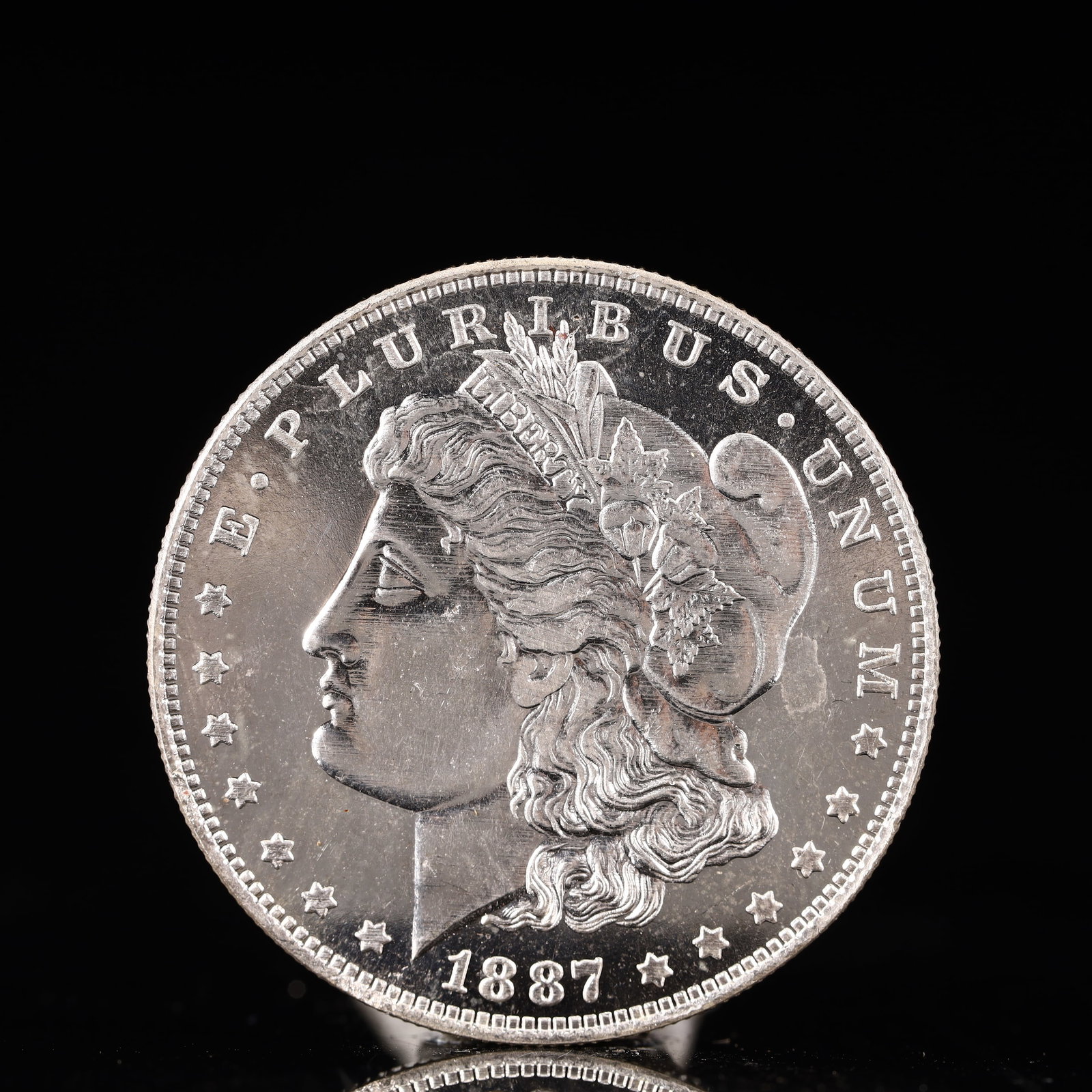 USA Morgan Dollar 1887 Coin: Obv: profile bust with date below and E PLURIBUS UNUM legend and stars around. Rev: eagle with In God we trust above within wreath with UNITED STATES OF AMERICA ONE DOLLAR legend. IN GOD WE TRUST / LI