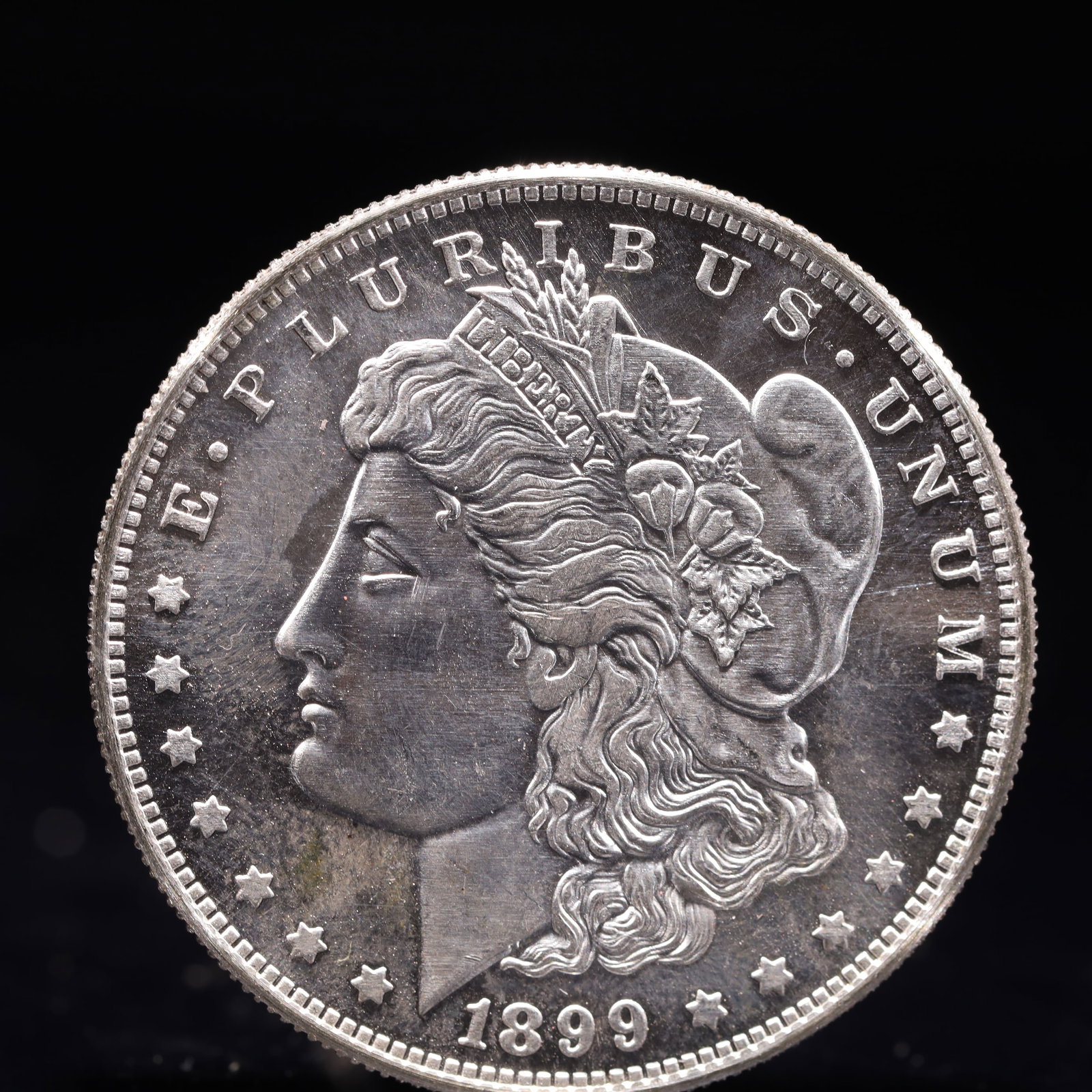 USA Morgan Dollar 1899 Coin: Obv: profile bust with date below and E PLURIBUS UNUM legend and stars around. Rev: eagle with In God we trust above within wreath with UNITED STATES OF AMERICA ONE DOLLAR legend. IN GOD WE TRUST / LI