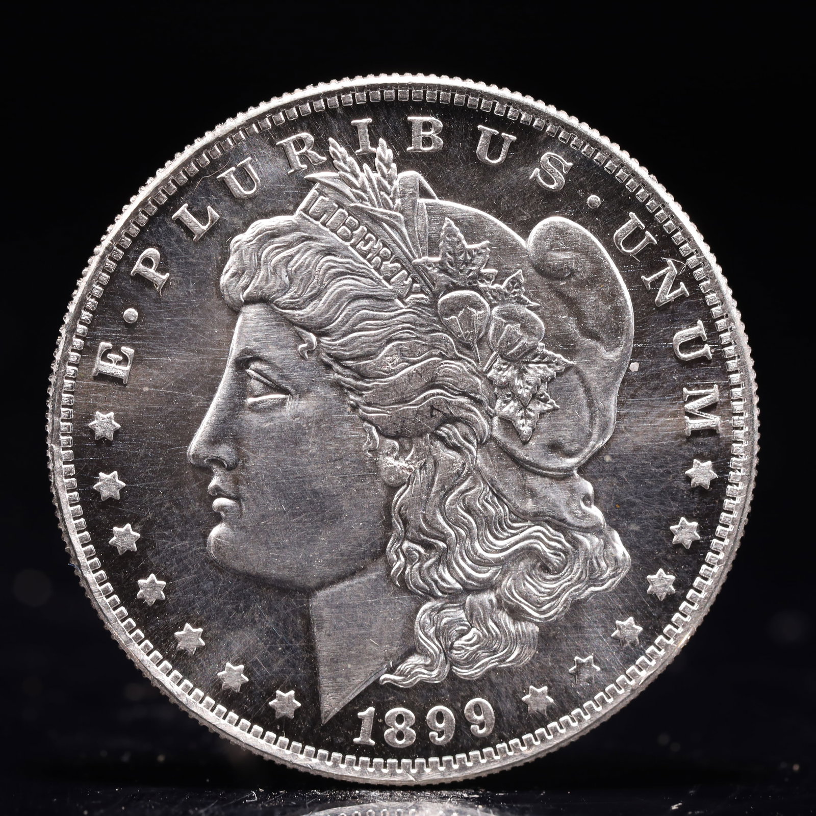USA Morgan Dollar 1899 Coin: Obv: profile bust with date below and E PLURIBUS UNUM legend and stars around. Rev: eagle with In God we trust above within wreath with UNITED STATES OF AMERICA ONE DOLLAR legend. IN GOD WE TRUST / LI