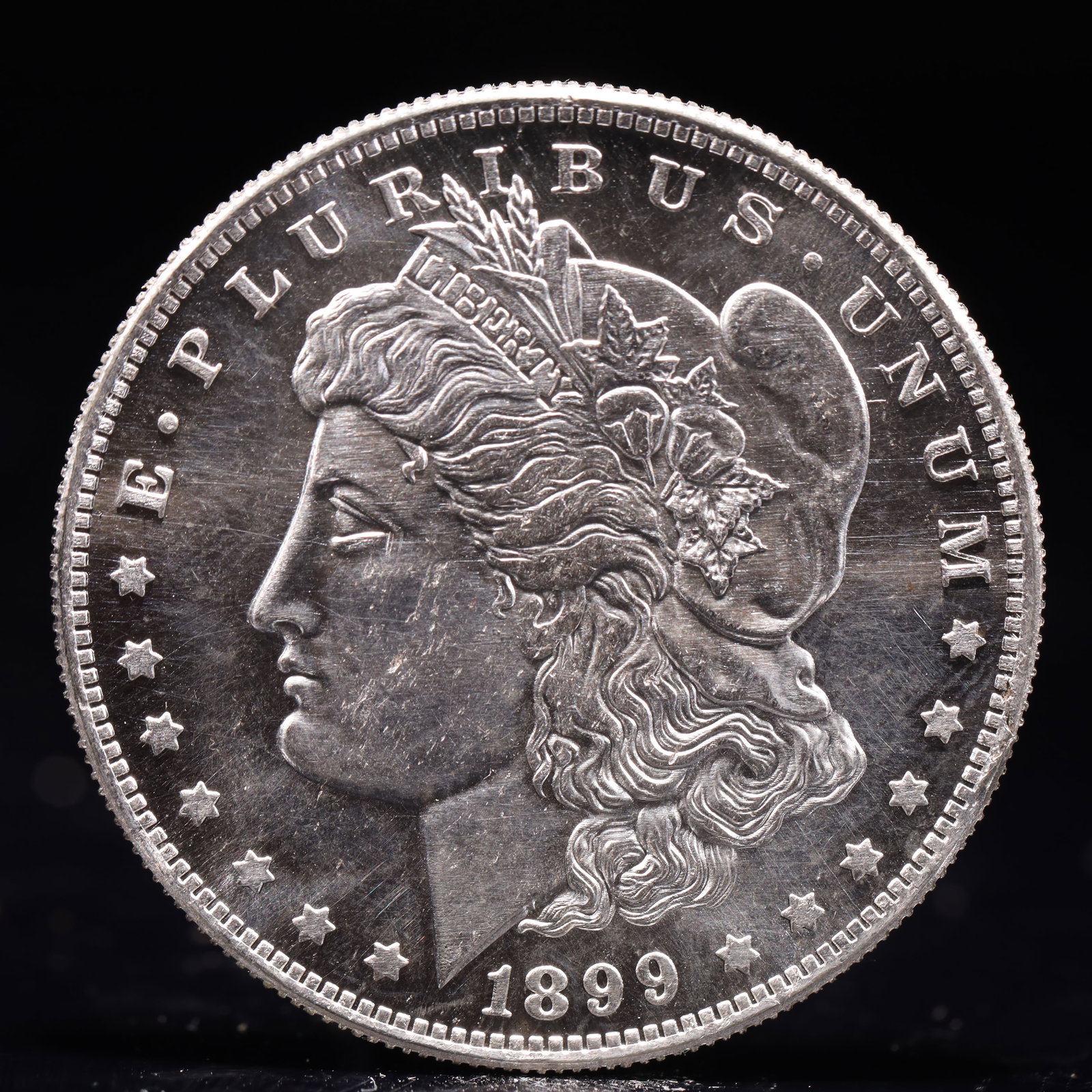 USA Morgan Dollar 1899 Coin: Obv: profile bust with date below and E PLURIBUS UNUM legend and stars around. Rev: eagle with In God we trust above within wreath with UNITED STATES OF AMERICA ONE DOLLAR legend. IN GOD WE TRUST / LI