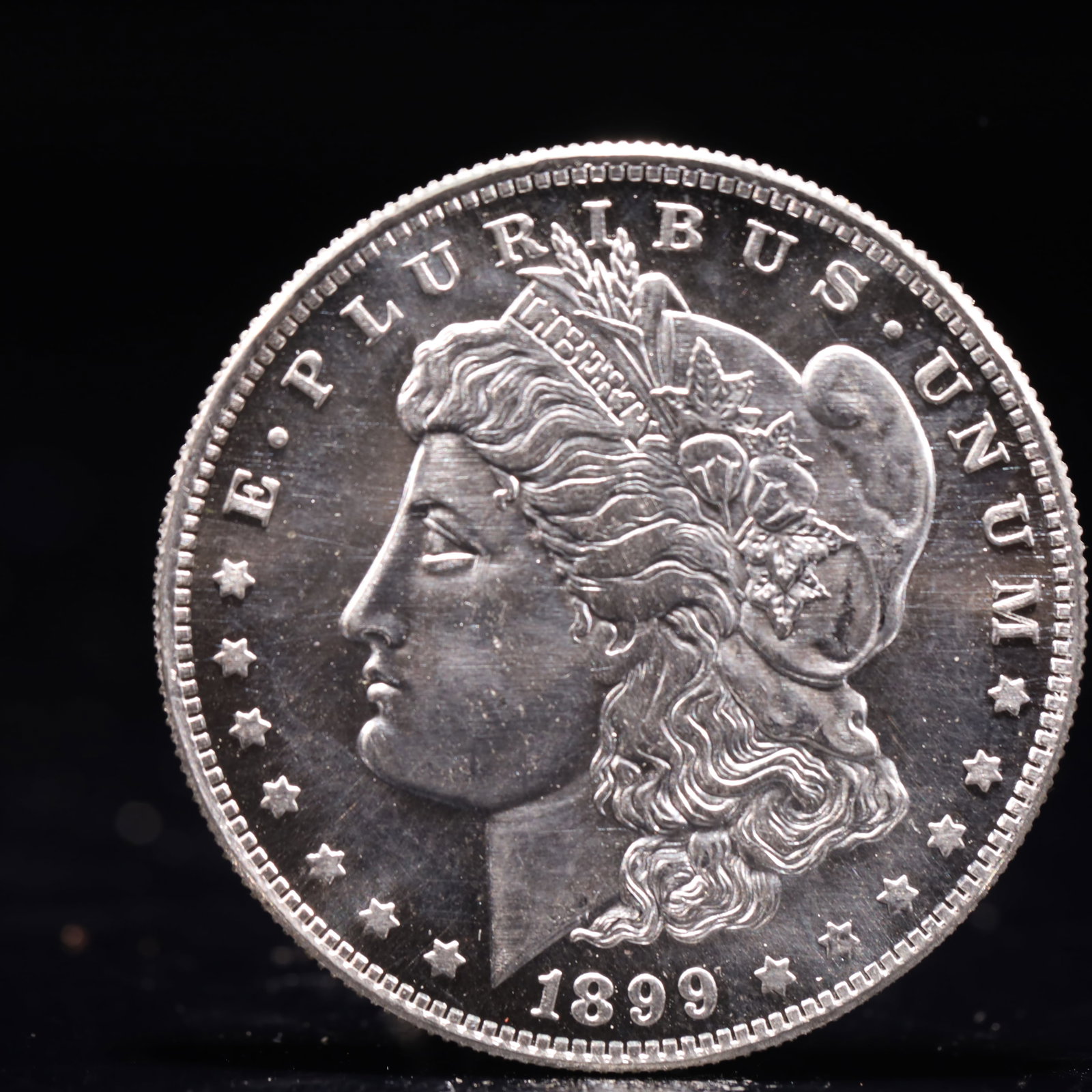USA Morgan Dollar 1899 Coin: Obv: profile bust with date below and E PLURIBUS UNUM legend and stars around. Rev: eagle with In God we trust above within wreath with UNITED STATES OF AMERICA ONE DOLLAR legend. IN GOD WE TRUST / LI