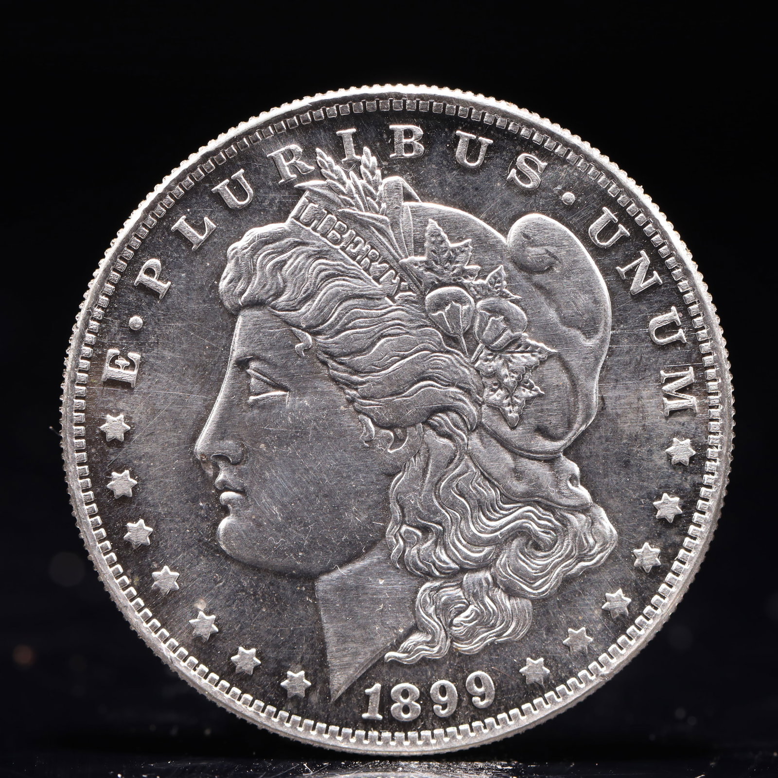 USA Morgan Dollar 1899 Coin: Obv: profile bust with date below and E PLURIBUS UNUM legend and stars around. Rev: eagle with In God we trust above within wreath with UNITED STATES OF AMERICA ONE DOLLAR legend. IN GOD WE TRUST / LI