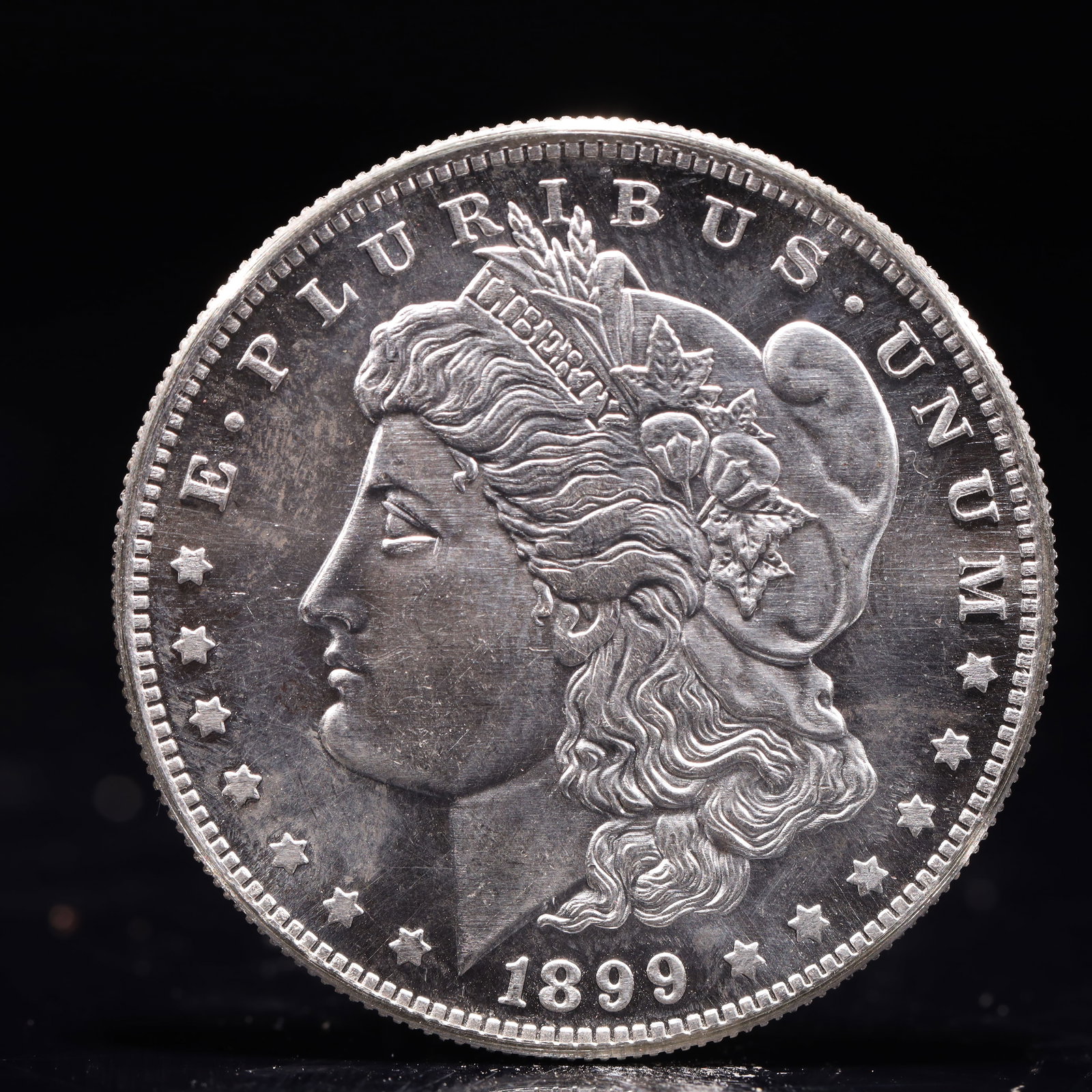 USA Morgan Dollar 1899 Coin: Obv: profile bust with date below and E PLURIBUS UNUM legend and stars around. Rev: eagle with In God we trust above within wreath with UNITED STATES OF AMERICA ONE DOLLAR legend. IN GOD WE TRUST / LI