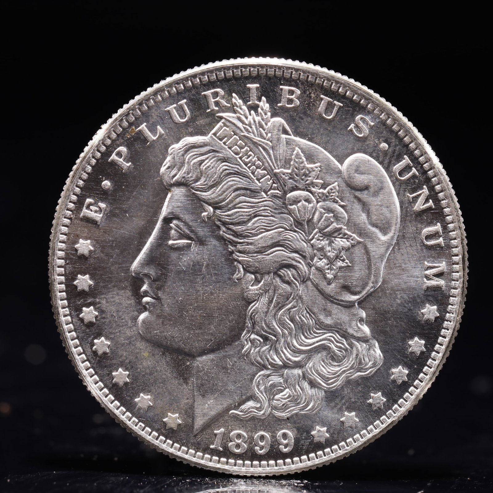 USA Morgan Dollar 1899 Coin: Obv: profile bust with date below and E PLURIBUS UNUM legend and stars around. Rev: eagle with In God we trust above within wreath with UNITED STATES OF AMERICA ONE DOLLAR legend. IN GOD WE TRUST / LI