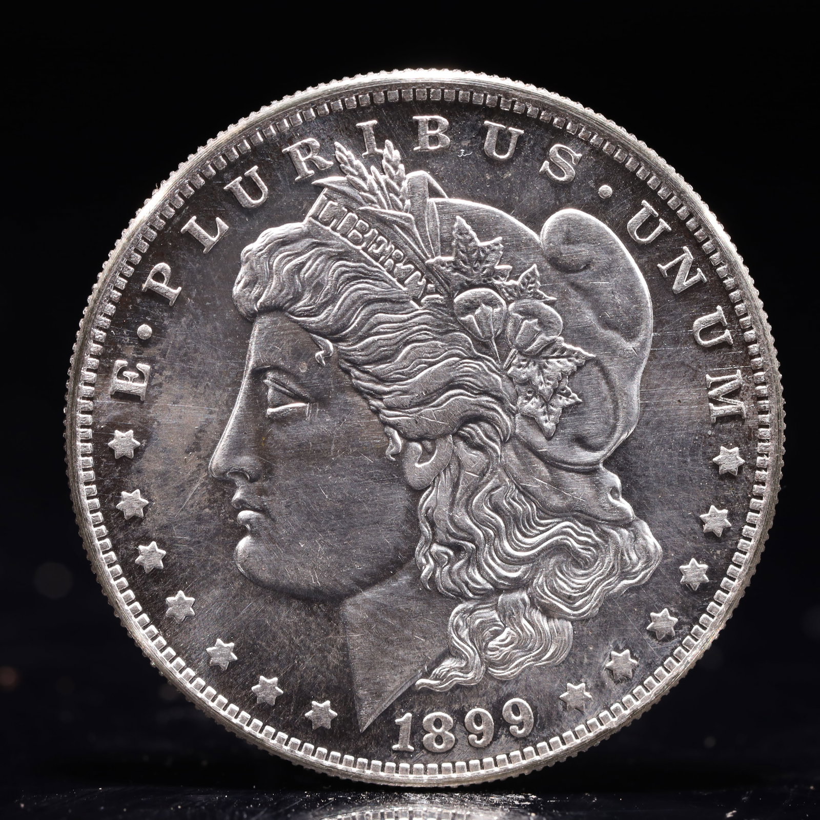 USA Morgan Dollar 1899 Coin: Obv: profile bust with date below and E PLURIBUS UNUM legend and stars around. Rev: eagle with In God we trust above within wreath with UNITED STATES OF AMERICA ONE DOLLAR legend. IN GOD WE TRUST / LI
