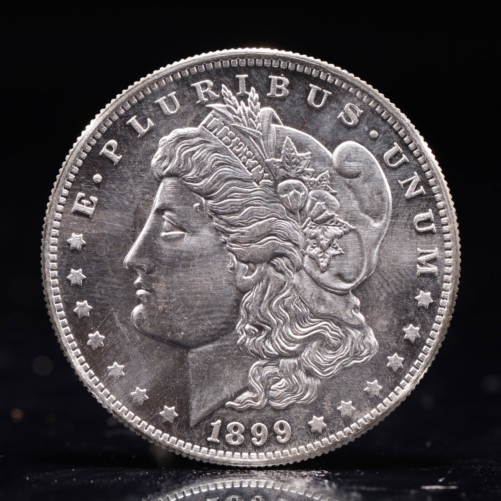 USA Morgan Dollar 1899 Coin: Obv: profile bust with date below and E PLURIBUS UNUM legend and stars around. Rev: eagle with In God we trust above within wreath with UNITED STATES OF AMERICA ONE DOLLAR legend. IN GOD WE TRUST / LI
