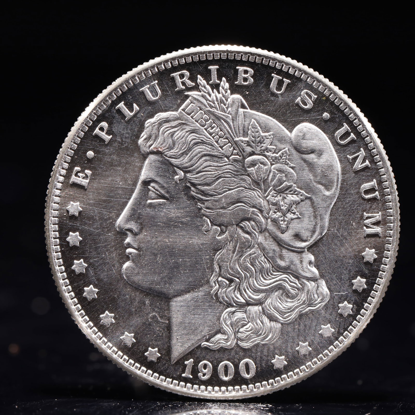 USA Morgan Dollar 1900 Coin: Obv: profile bust with date below and E PLURIBUS UNUM legend and stars around. Rev: eagle with In God we trust above within wreath with UNITED STATES OF AMERICA ONE DOLLAR legend. IN GOD WE TRUST / LI