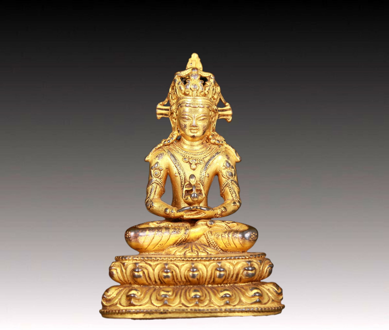An exquisite gilt bronze statue of Amitayus Buddha: An exquisite gilt bronze statue of Amitayus Buddha,Ming Dynasty,China. The Buddha's face has clear outlines,deep eyes,a solemn and kind expression,and the corners of his mouth are slightly