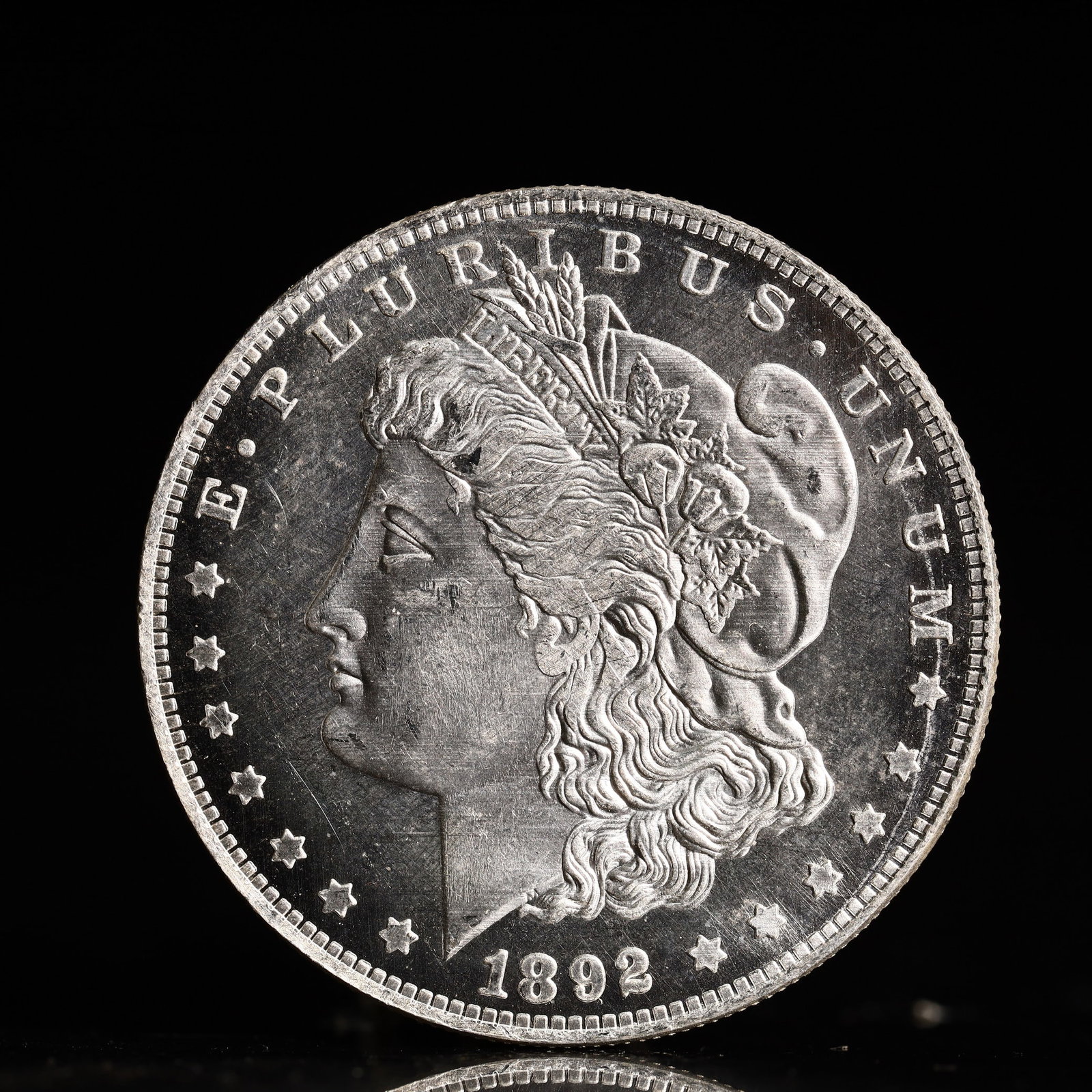 USA Morgan Dollar 1892 Coin: Obv: profile bust with date below and E PLURIBUS UNUM legend and stars around. Rev: eagle with In God we trust above within wreath with UNITED STATES OF AMERICA ONE DOLLAR legend. IN GOD WE TRUST /