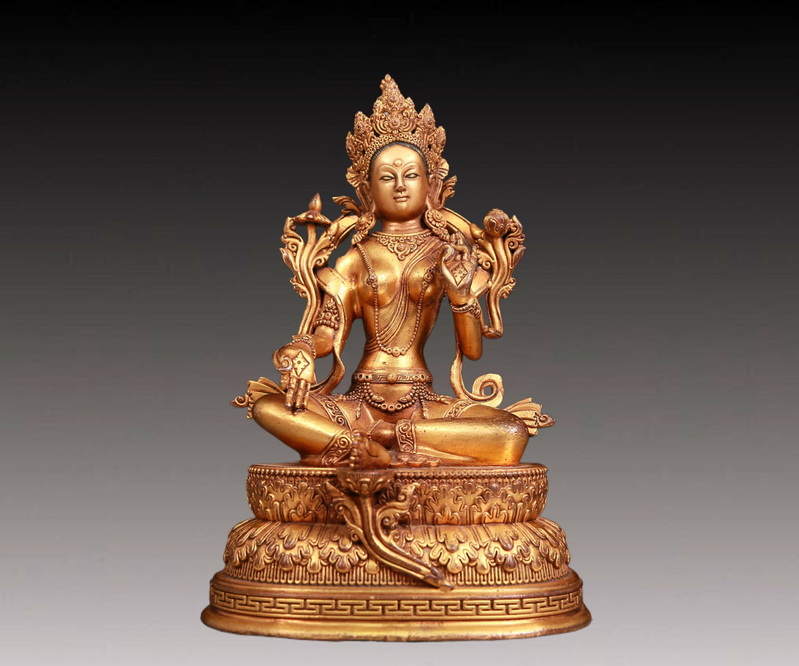 A solemn gilt bronze statue of green Tara: A solemn gilt-bronze green Tara statue with inscription,Ming Dynasty,China. Tara's posture is elegant,with a peaceful and compassionate expression. Her face is soft and A solemn,and her eyes are warm,
