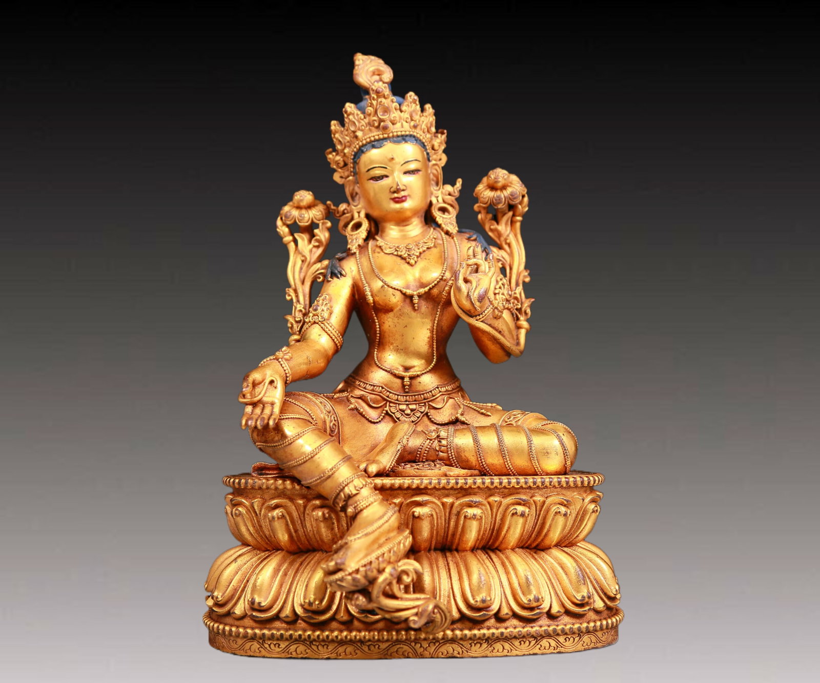 A solemn gilt bronze statue of green Tara: A solemn gilt-bronze green Tara statue,Ming Dynasty,China. Tara has an elegant posture with a peaceful and compassionate expression. Her face is soft and A solemn,and her eyes are warm. She seems to b