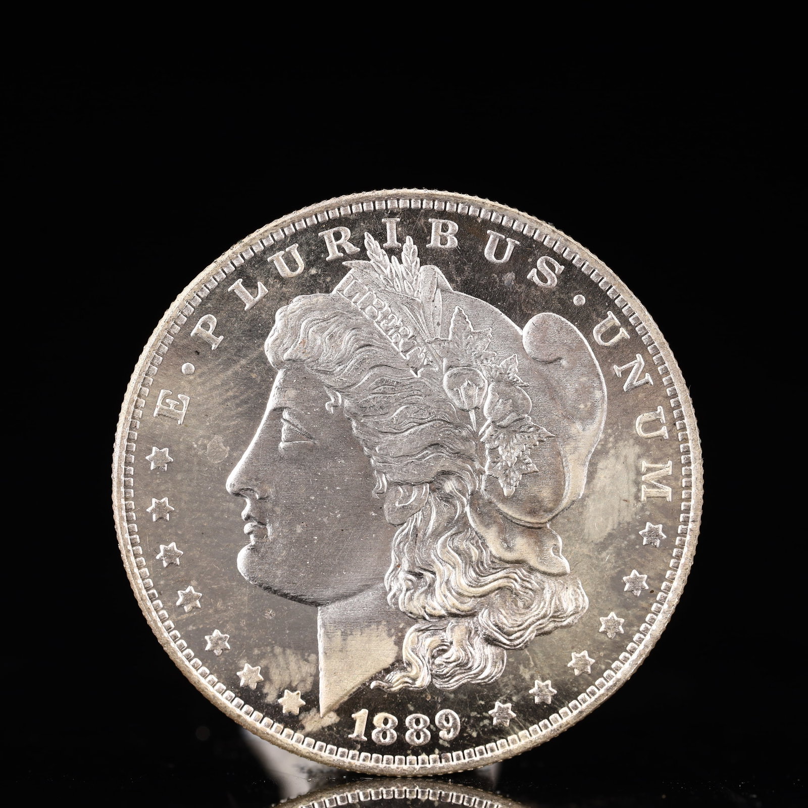 USA Morgan Dollar 1889 Coin: Obv: profile bust with date below and E PLURIBUS UNUM legend and stars around. Rev: eagle with In God we trust above within wreath with UNITED STATES OF AMERICA ONE DOLLAR legend. IN GOD WE TRUST / LI