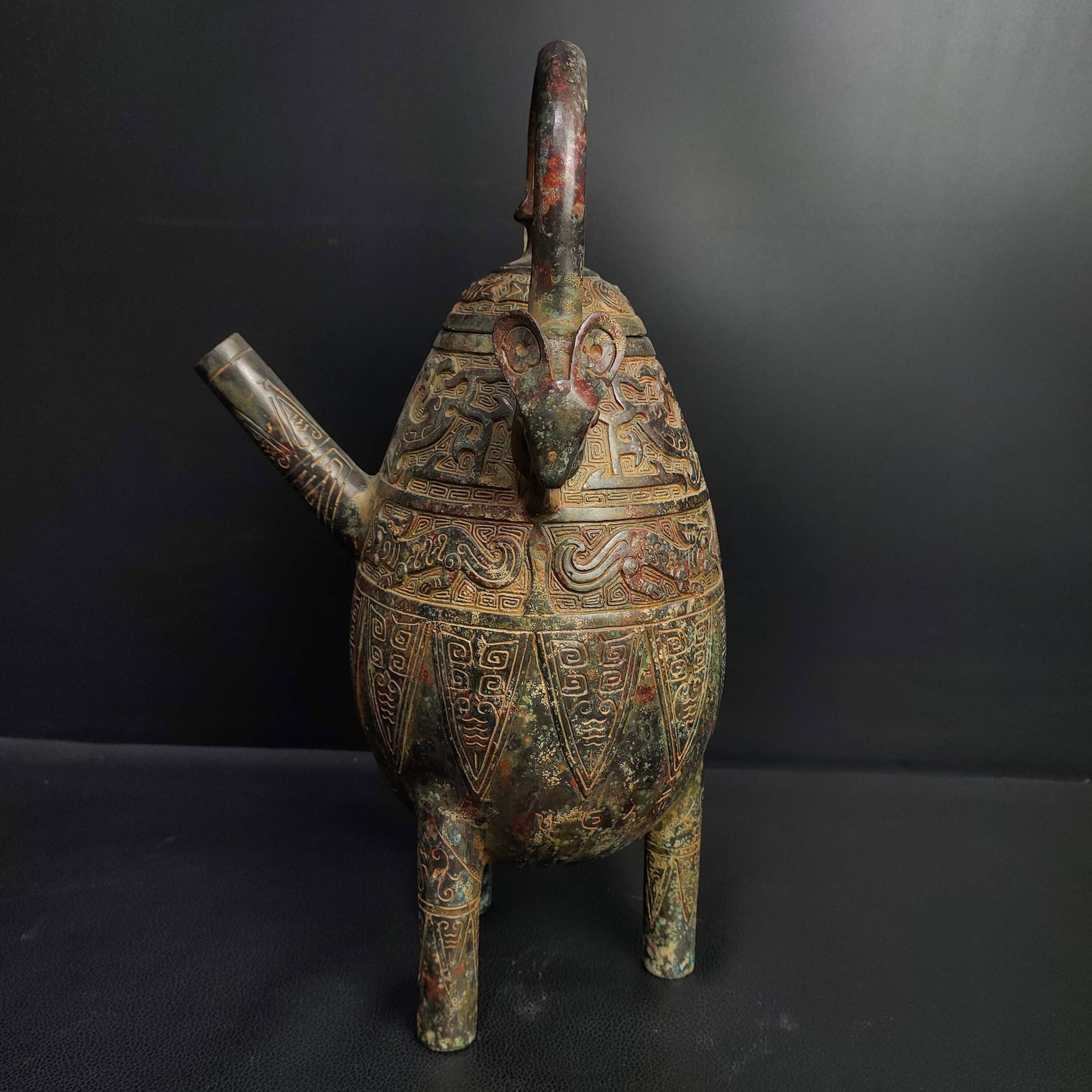 An Archaic Bronze Auspicious Beast Pattern Tripod Loop-Handled Pot,With Inscription: An Archaic Bronze Auspicious Beast Pattern Tripod Loop-Handled Pot,With Inscription,the Shang and Zhou Dynasties of China,Size:13inx7.9in,Weight:2000g青铜瑞兽纹三&#