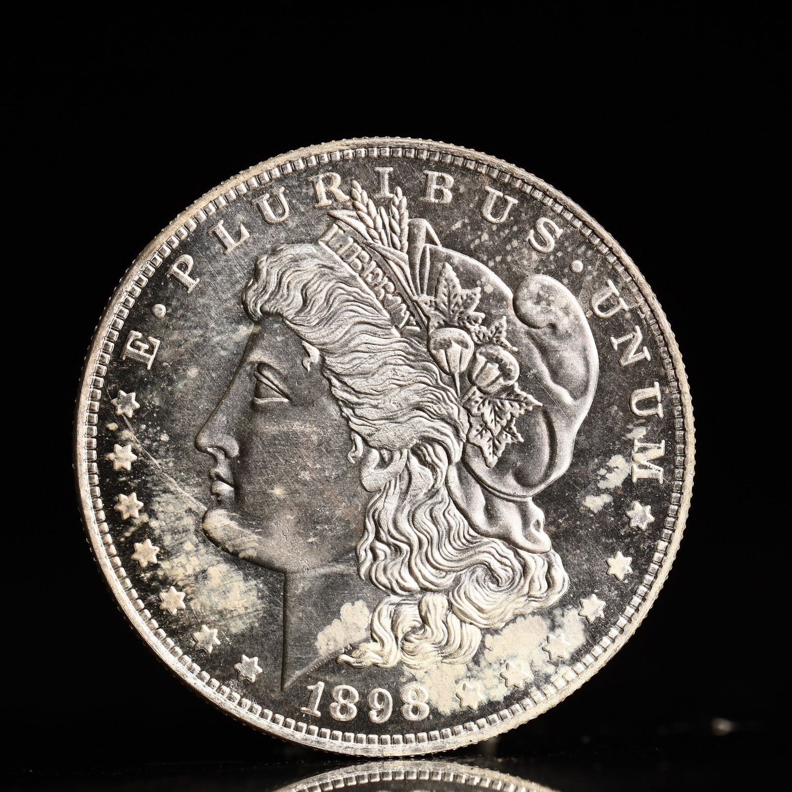 USA Morgan Dollar 1898 Coin: Obv: profile bust with date below and E PLURIBUS UNUM legend and stars around. Rev: eagle with In God we trust above within wreath with UNITED STATES OF AMERICA ONE DOLLAR legend. IN GOD WE TRUST / LI