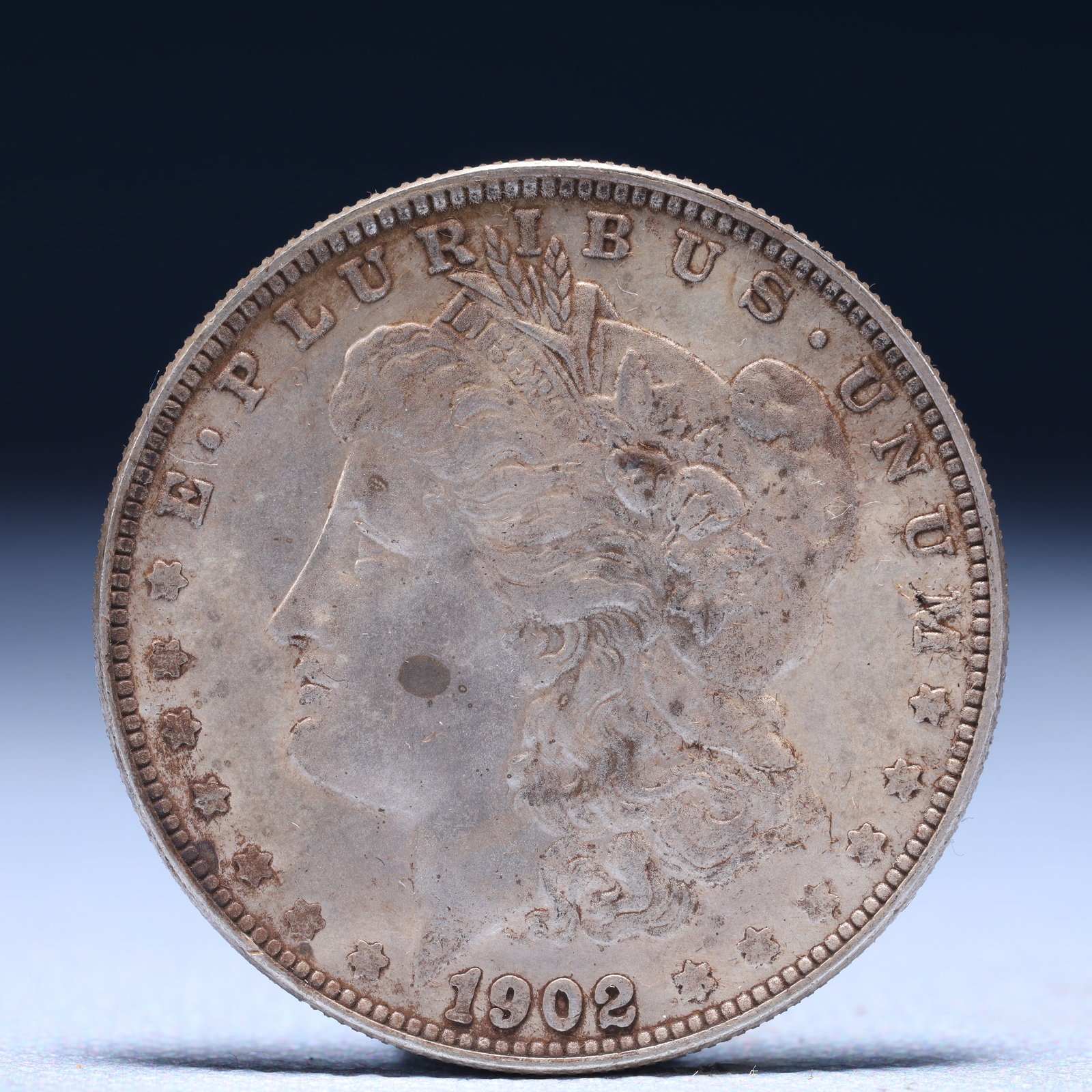 USA Morgan Dollar 1902 Coin: Obv: profile bust with date below and E PLURIBUS UNUM legend and stars around. Rev: eagle with In God we trust above within wreath with UNITED STATES OF AMERICA ONE DOLLAR legend. IN GOD WE TRUST / LI