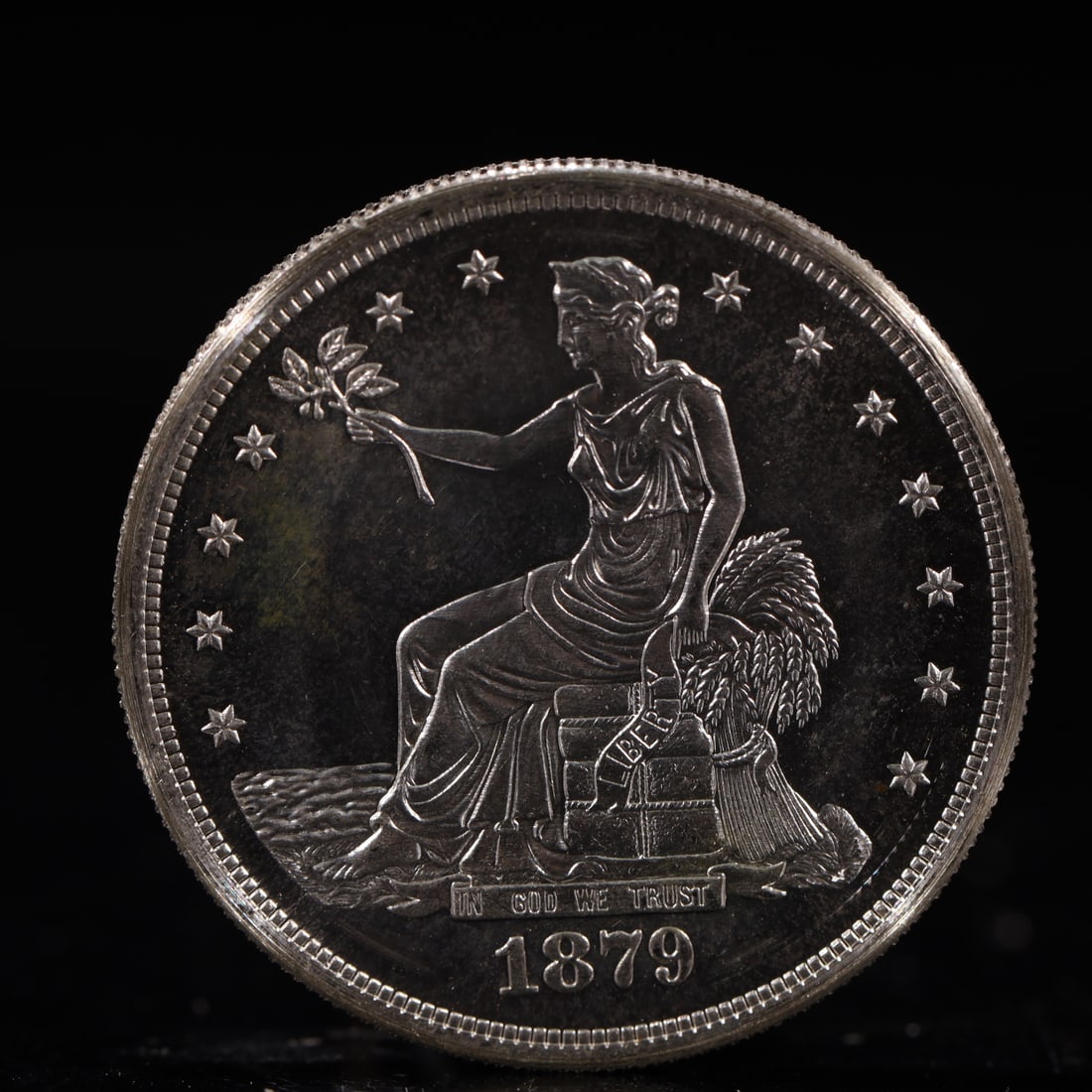 USA Trade Dollar 1879 Coin: American coin. Obverse: Liberty seated on a pedestal facing the sea to the left holding olive branches surrounded by 13 stars. IN GOD WE TRUST / LIBERTY / 1879. Reverse: An eagle holding branches with