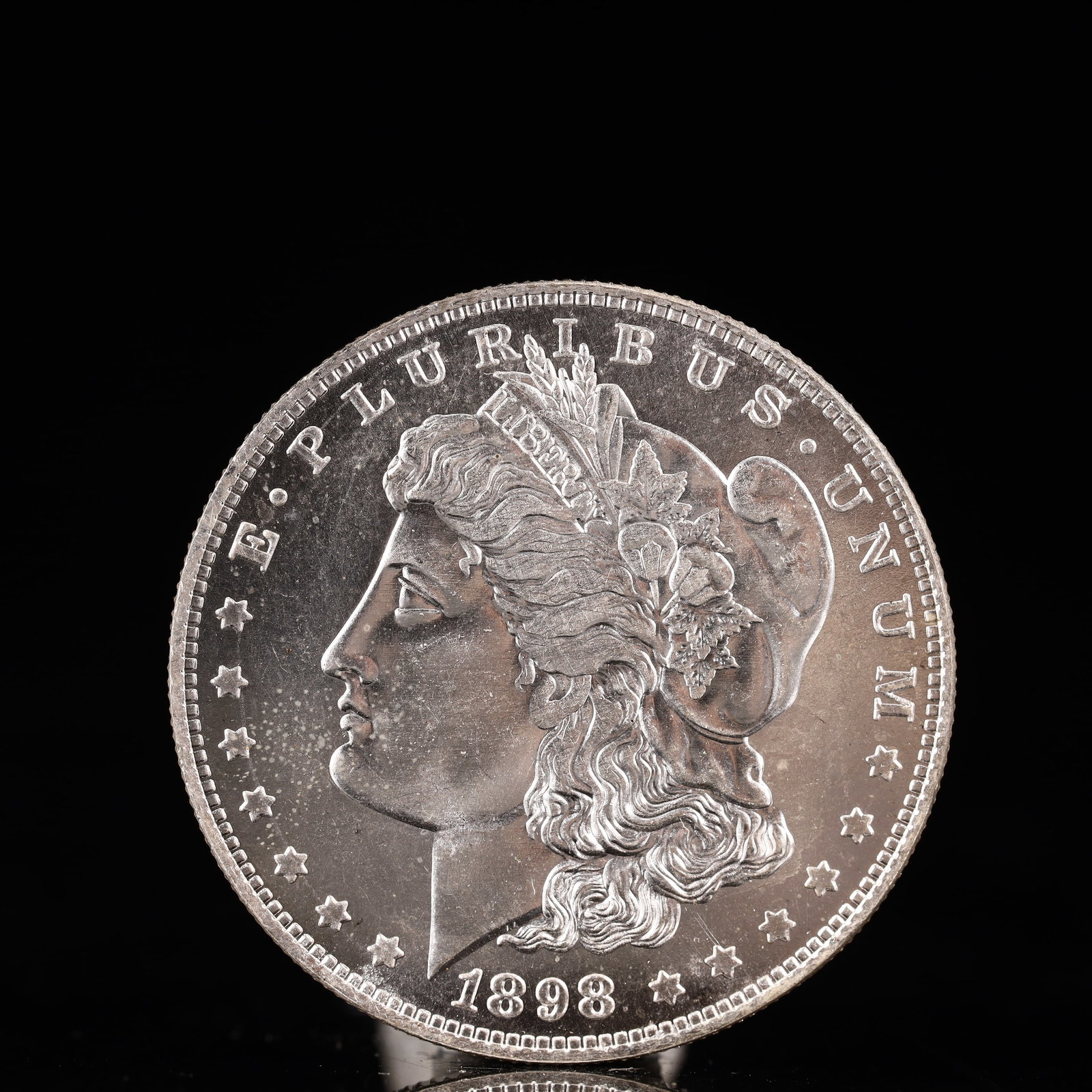 USA Morgan Dollar 1898 Coin: Obv: profile bust with date below and E PLURIBUS UNUM legend and stars around. Rev: eagle with In God we trust above within wreath with UNITED STATES OF AMERICA ONE DOLLAR legend. IN GOD WE TRUST / LI